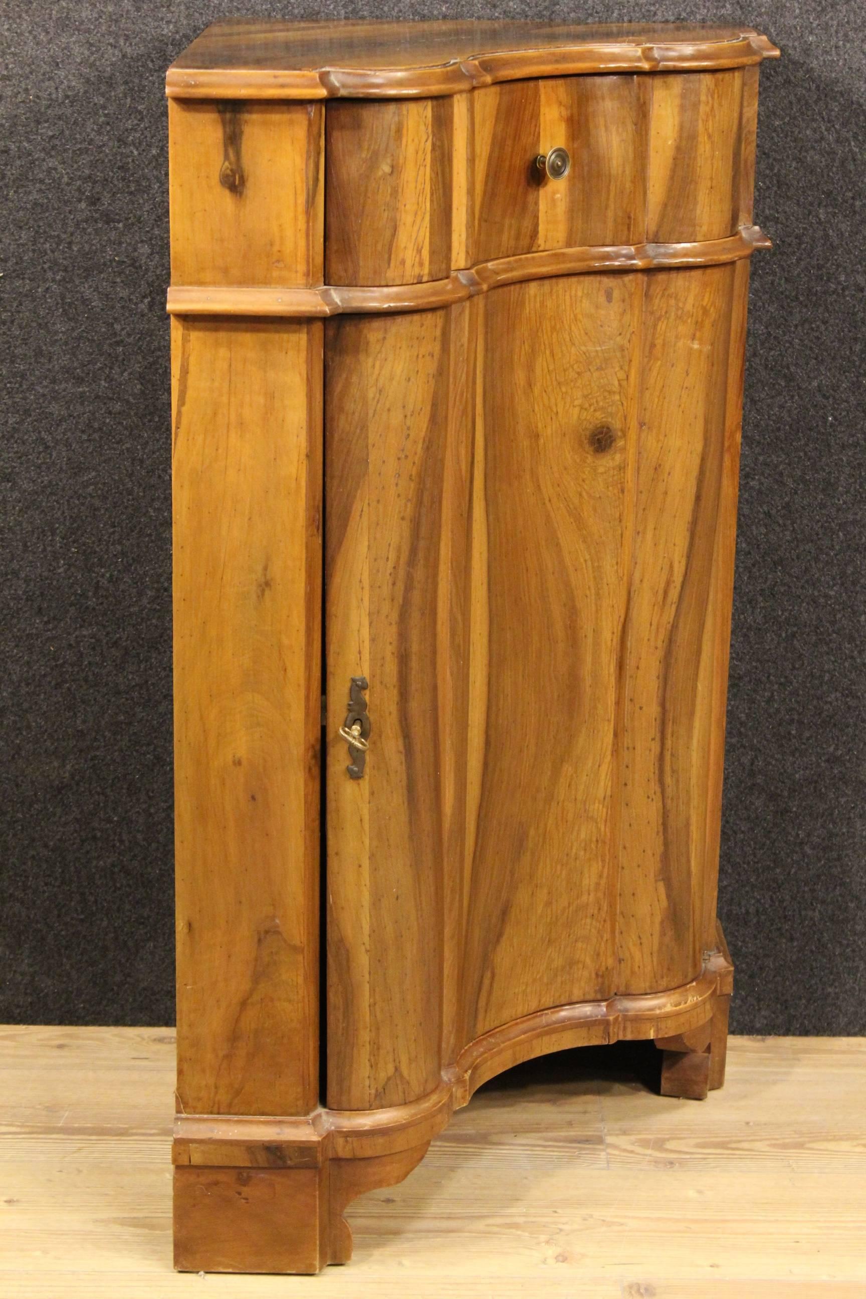 Corner cupboard made by carved walnut. Italian furniture of the 20th century hard to find. Cupboard with one door with an internal shelf and a top drawer of great service. Corner cupboard supported by three legs, of good stability. It shows some
