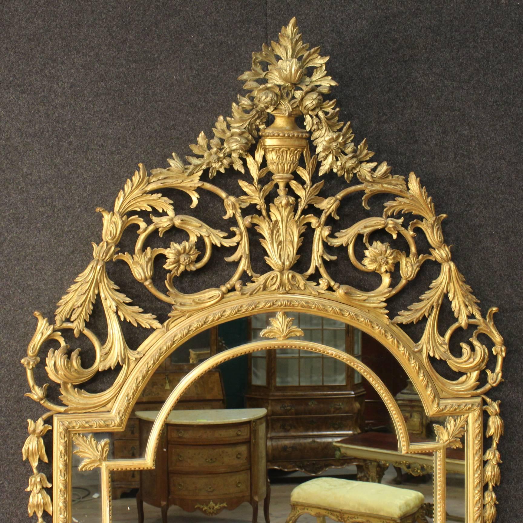 Big Italian mirror of the 20th century. Furniture of beautiful line and good taste in Louis XVI style, made by richly carved and gilded wood. Mirror of great impact pleasantly adorned with floral decorations. Furniture ideal to be placed into a