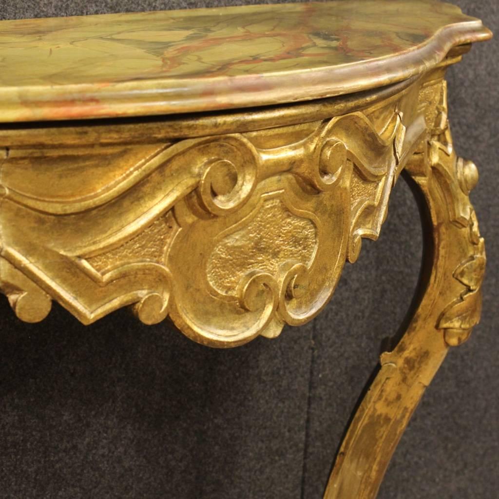 Beautiful Italian console table of the 20th century. Furniture in nicely carved and gilded wood, of great taste and nice decoration. Console to be fixed to the wall for a perfect stability supported by two frontal legs. Top in lacquered faux marble