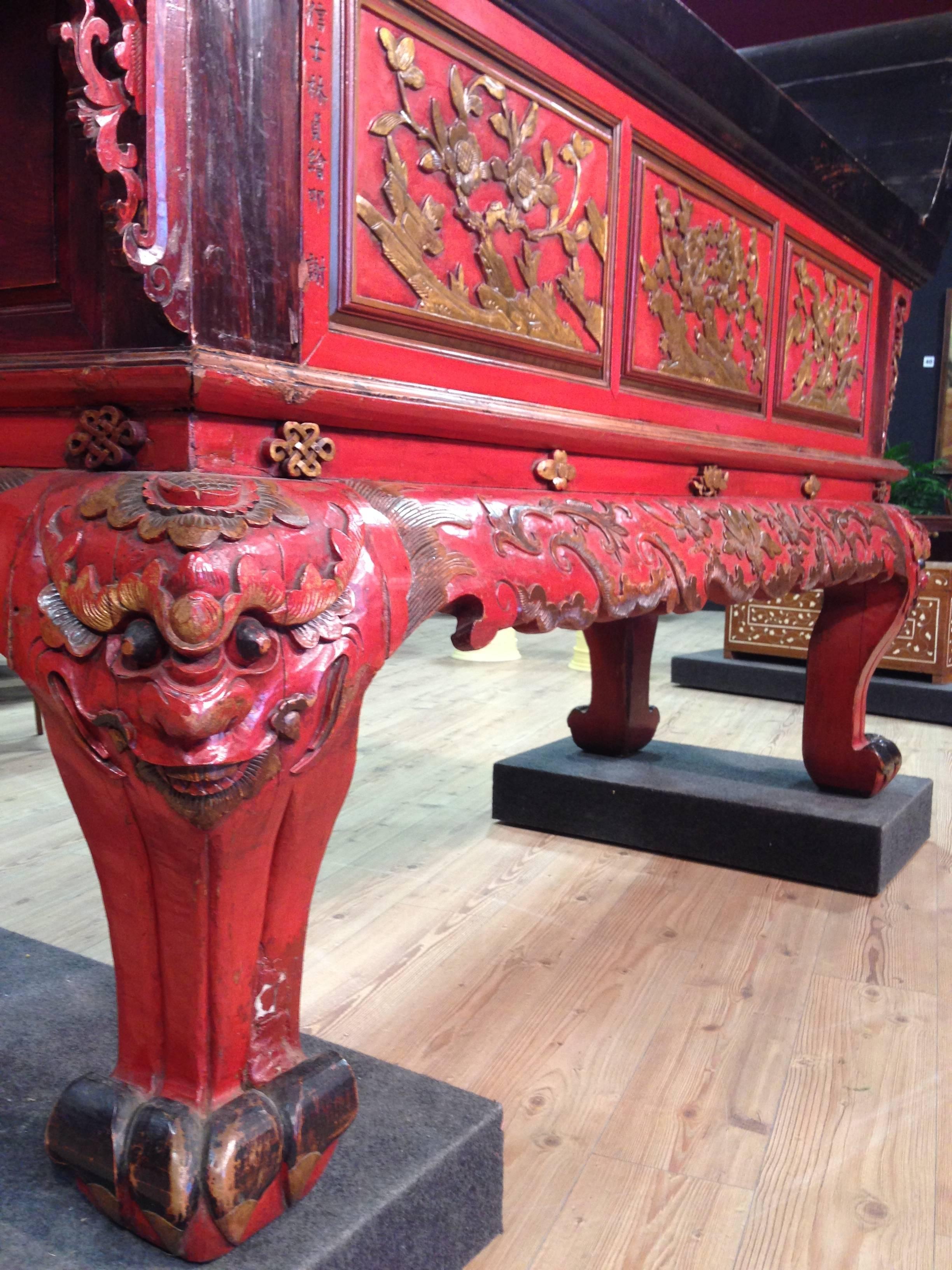 Chinese console table of the early 20th century. High quality furniture in ornately carved, painted and gilded wood with masks and floral decorations. Console table with four legs and feral carved feet, signed on a panel. Rare furniture of