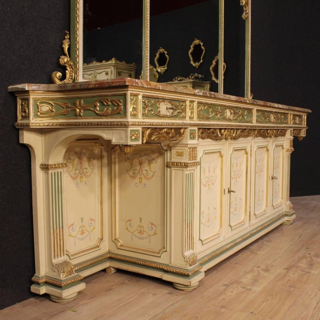 Spectacular Italian sideboard with mirror of the mid-20th century. Furniture in ornately carved, lacquered, gilded and hand-painted wood, of great quality and fabulous decoration. Sideboard with four doors and four drawers, of large capacity and