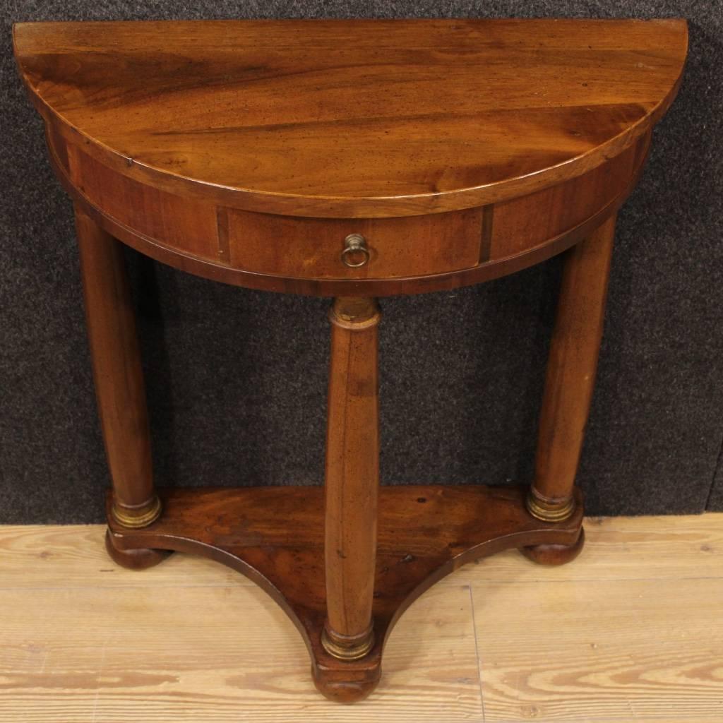 Small Italian console table of the second half of the 20th century. Furniture in carved wood pleasantly decorated with chiseled brass in Empire style. Demi lune console table supported by three columns, top floor in character, of discreet measure