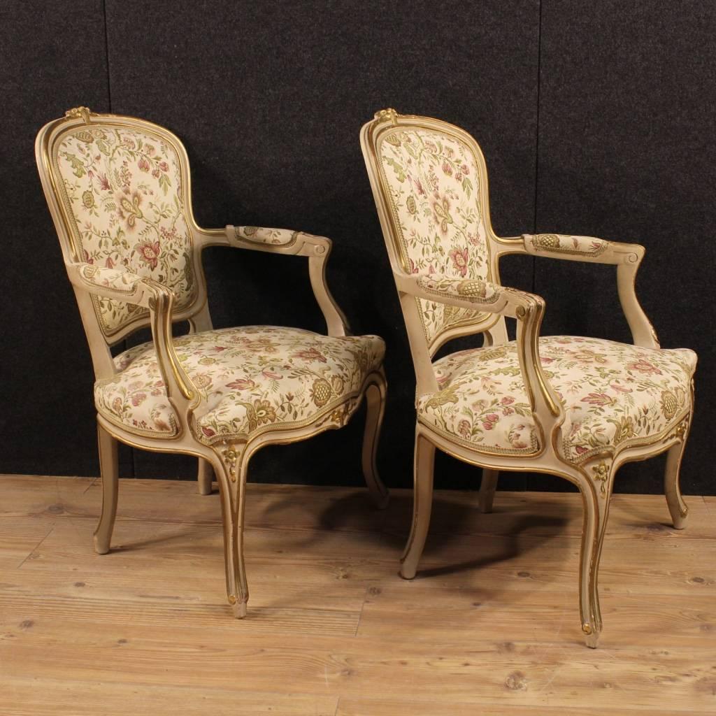 Pair of Italian armchairs of the mid-20th century. Furniture in nicely carved, lacquered and gilded wood of great decoration. Armchairs covered with floral fabric, in excellent condition. Comfortable seats with upholstery in perfect condition.