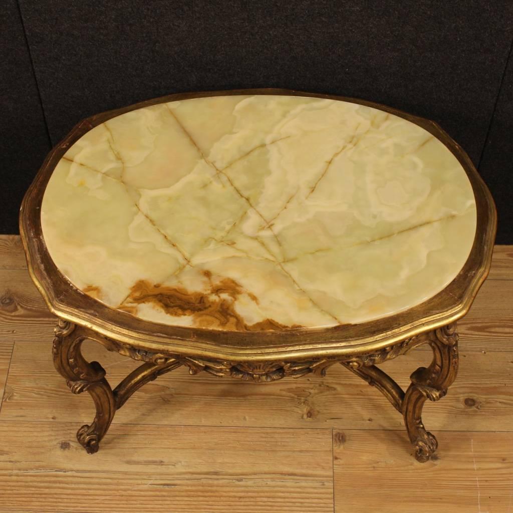 Italian coffee table of the 20th century. Furniture in carved and golden wood and plaster of beautiful decoration. Top in onyx of good measure and service. Living room table by pleasant decor. It presents some minor gilding drops on the whole in