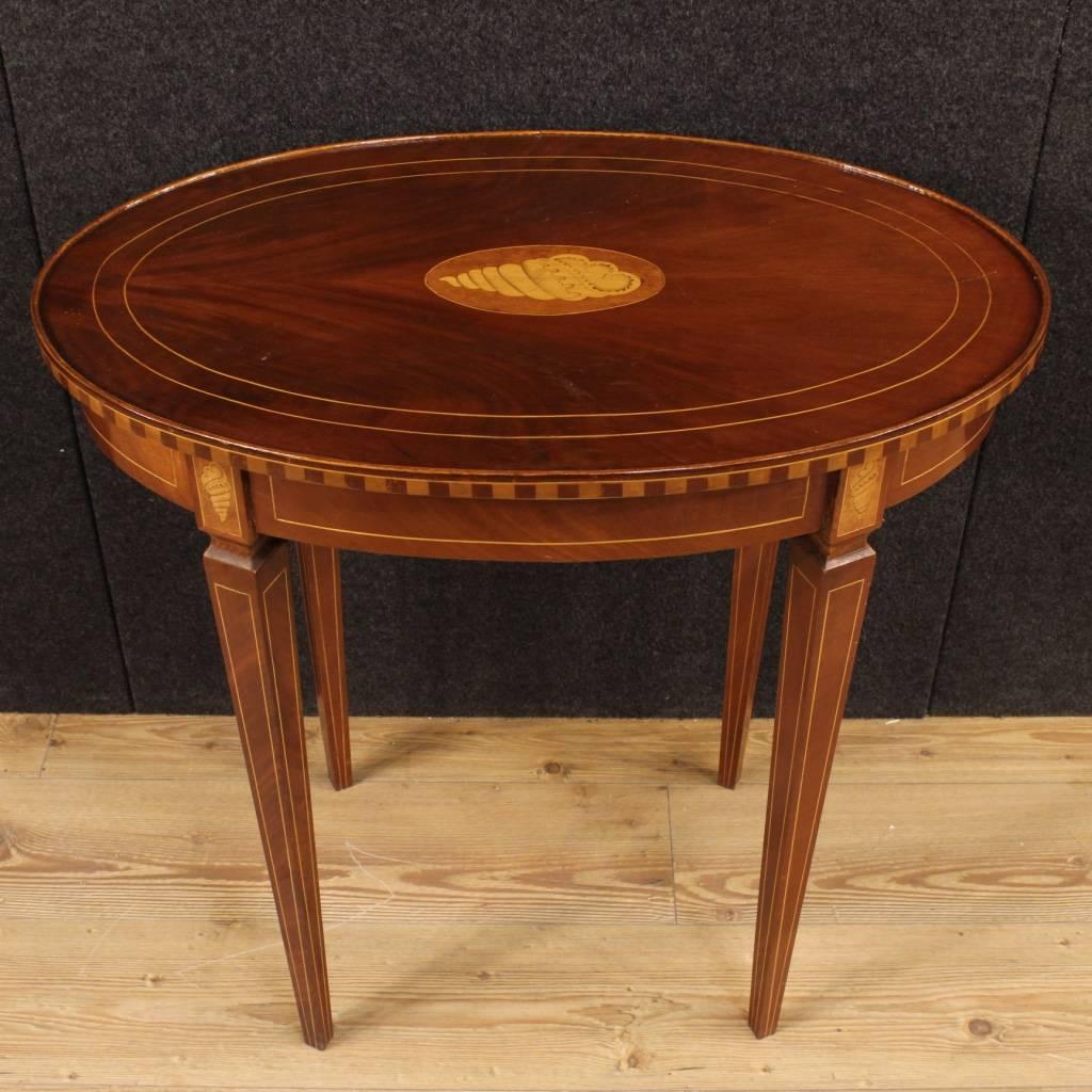 Inlaid side table of the 20th century. English furniture in mahogany with thread and central inlaid shell-shaped. Oval living room table of discrete size and service. Furniture supported by four legs also inlaid, of good stability. High proportion