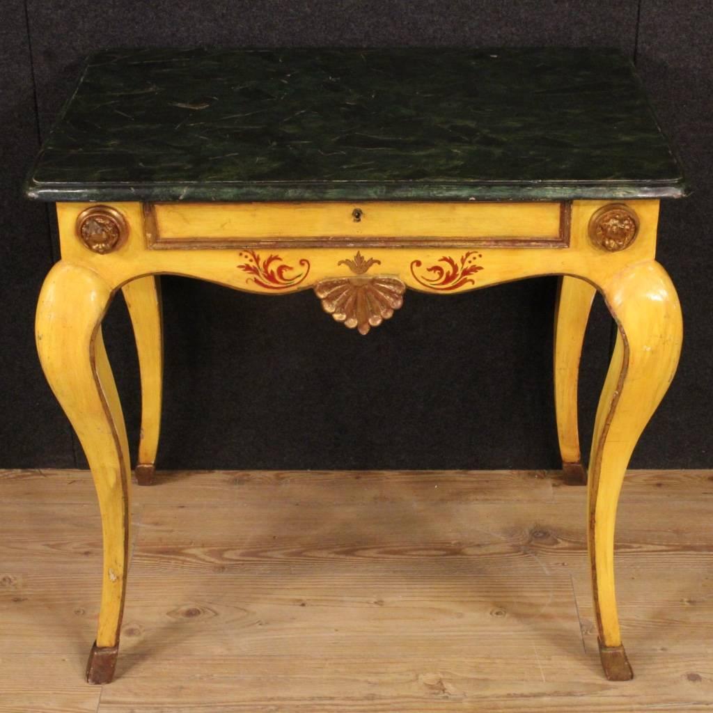 Italian side table of the 20th century. Furniture of high quality in carved, lacquered, gilded and painted by hand wood. Top in wood, lacquered faux marble, of good measure and service. Side table finished for the centre decorated with the faces of