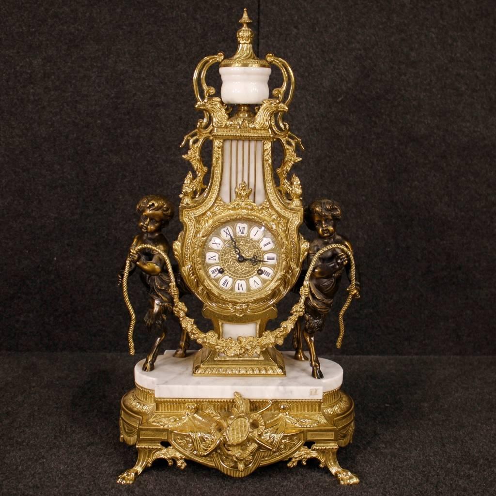 Clock with candlesticks, Germany, second half of 20th century. Triptych in marble, golden and chiselled metal and bronze little angels sculptures. Each candlestick has seven lights of great measure and fabulous decoration. Clock with mechanism and