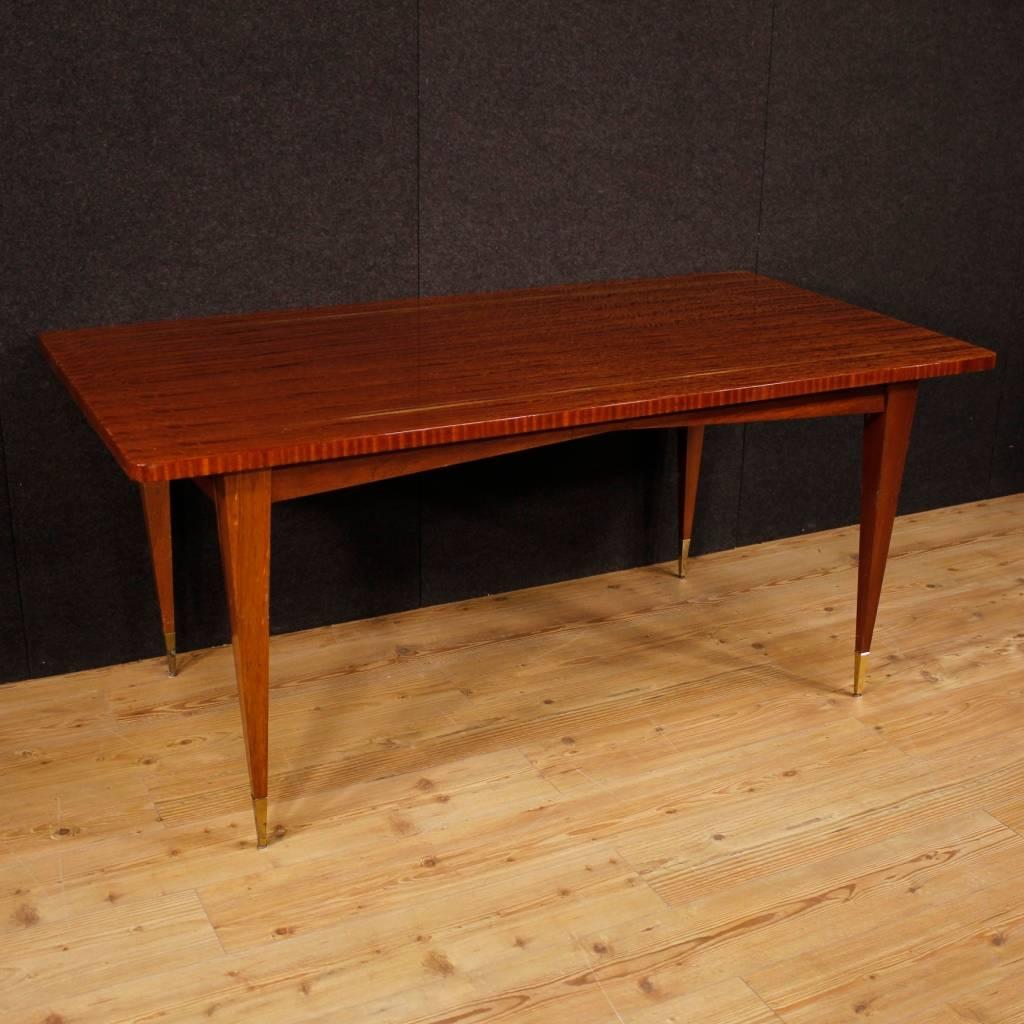 Italian design table of the second half of the 20th century. Furniture in mahogany with golden brass inlay of beautiful line and nice furnishings. Furniture of good stability and solidity supported by four leg with brass feet. Dining table of