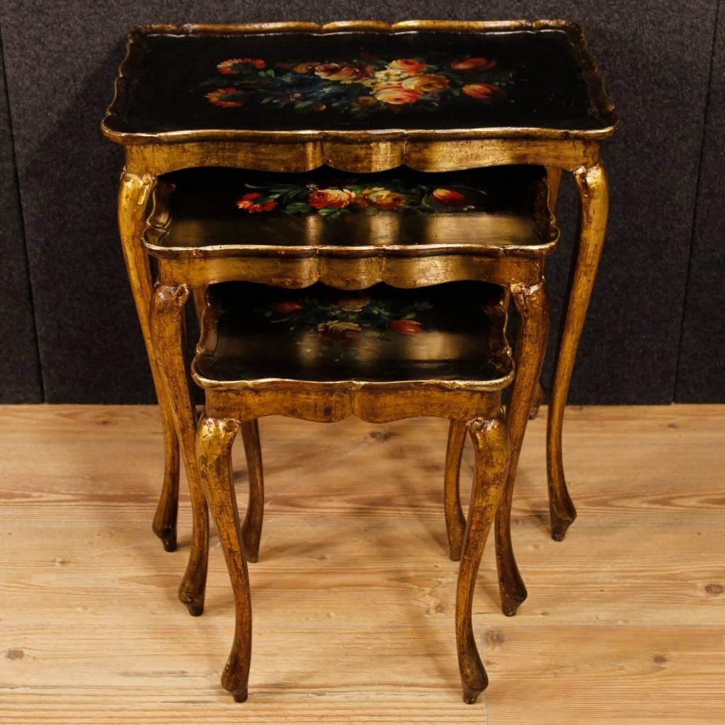 Triptych of florentine coffee tables of the 20th century. Carved, golden, lacquered and hand-painted wooden furniture with floral decorations on the tops. Coffee tables of three different sizes, ideal for inserting into a living room. Tables of good
