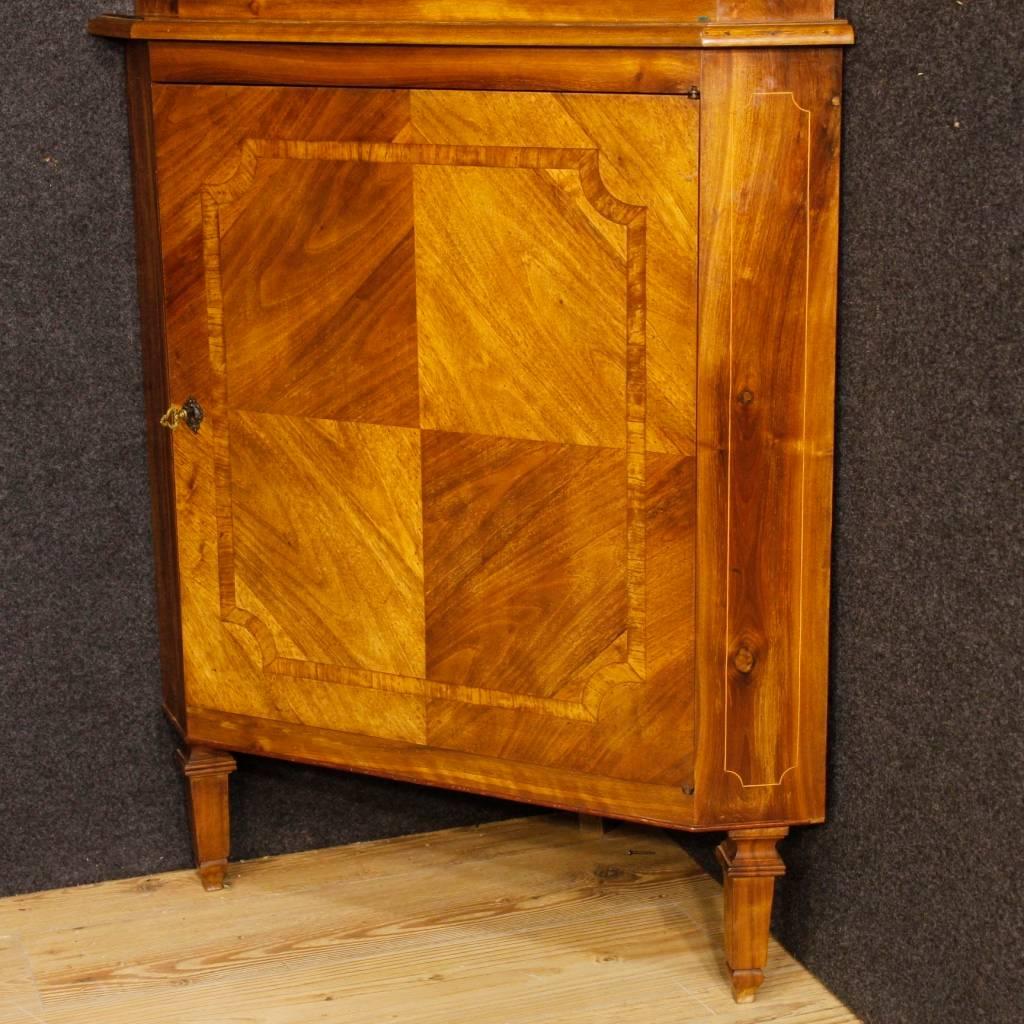 Italian corner cupboard in Louis XVI style from the mid-twentieth century. Double body furniture in carved in walnut wood with boxwood thread. Corner cabinet with two doors of good capacity and service, complete with two working keys. Upper body