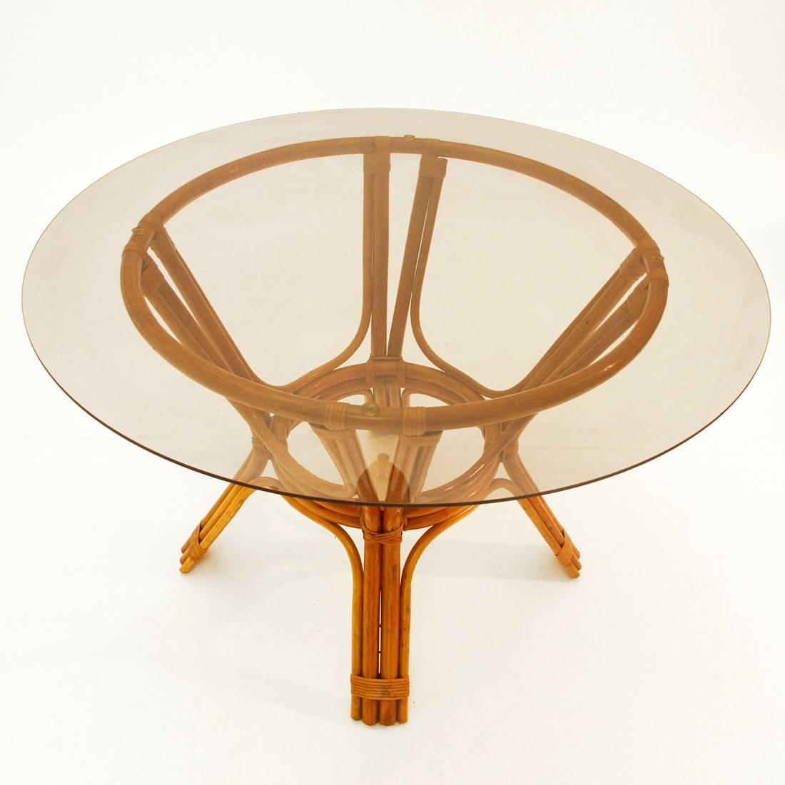This table was designed in the 1970s and produced in Italy. It features a bamboo structure and a circular glass top.
