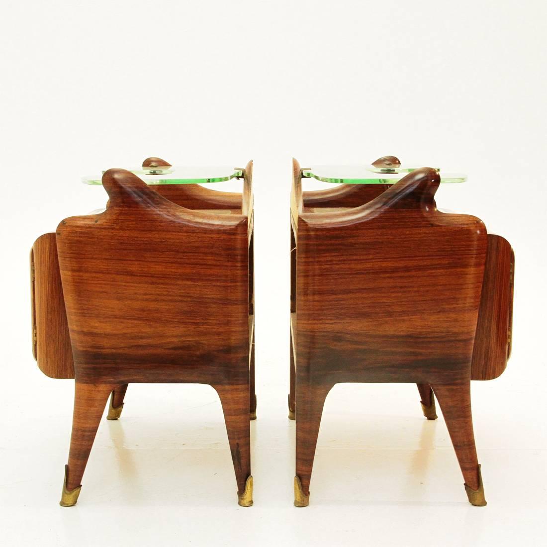 High refined pair of nightstands attributed to Paolo Buffa.
The nightstands have rosewood Herringbone pattern veneer with brass hardware and foots, colored glass top and a 