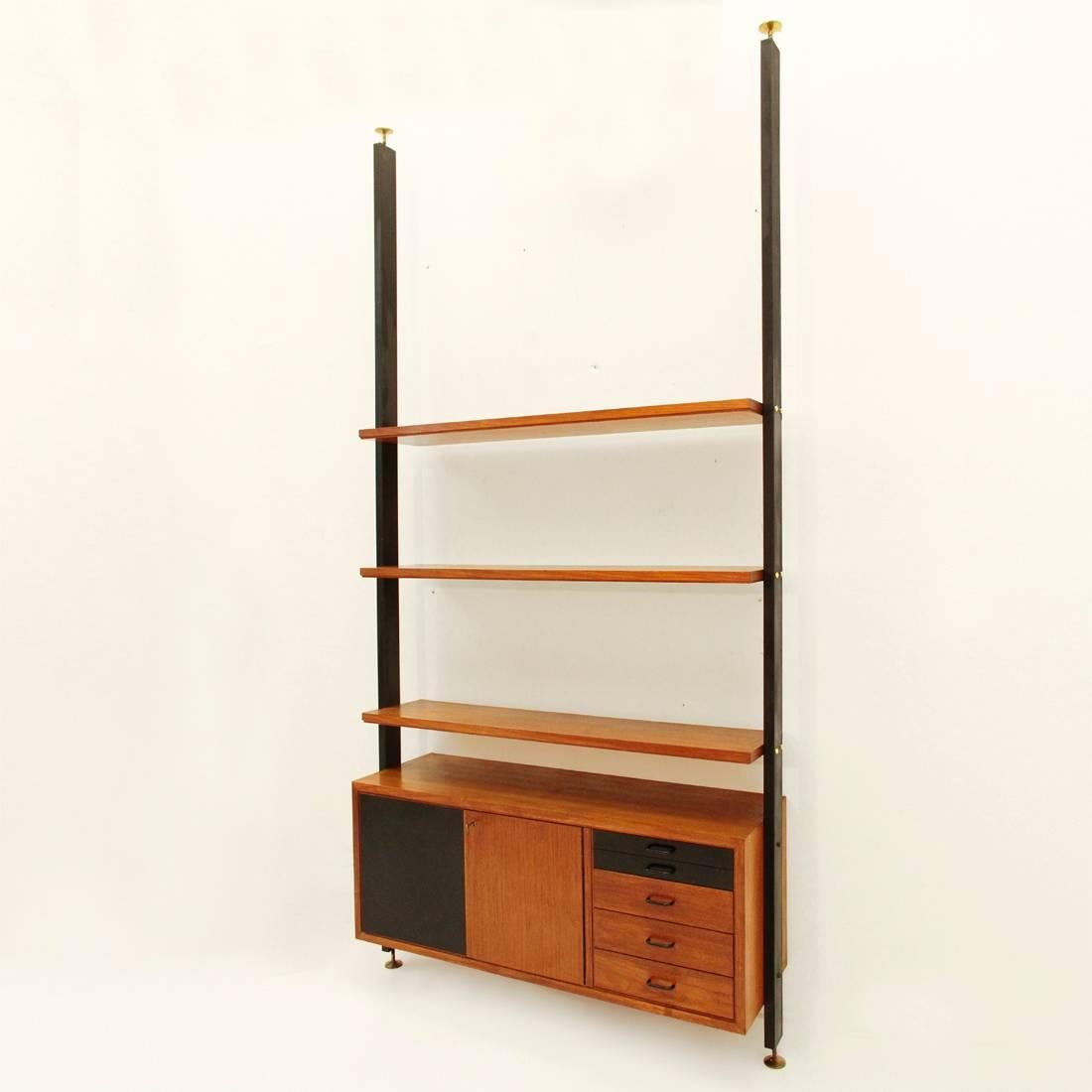 Bookshelf manufactured in the 1960s. It features iron uprights and wooden elements with a teak veneer. This single module bookshelf consists of three shelves and wall cabinet with two doors and four drawers. Fair vintage condition, defects and signs
