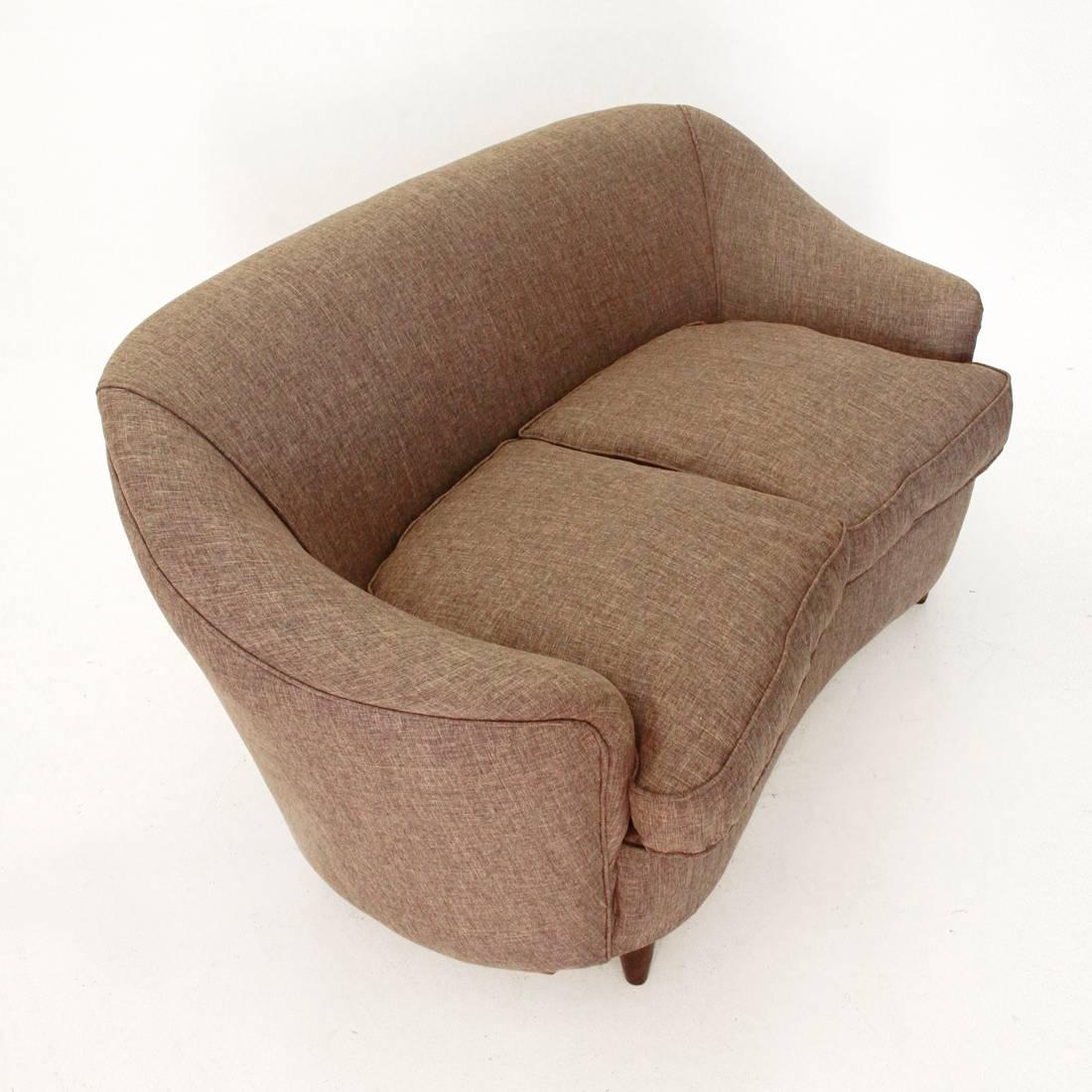 This two-seat sofa was made in Italy and features a curved structure, two cushions and wooden feet.
