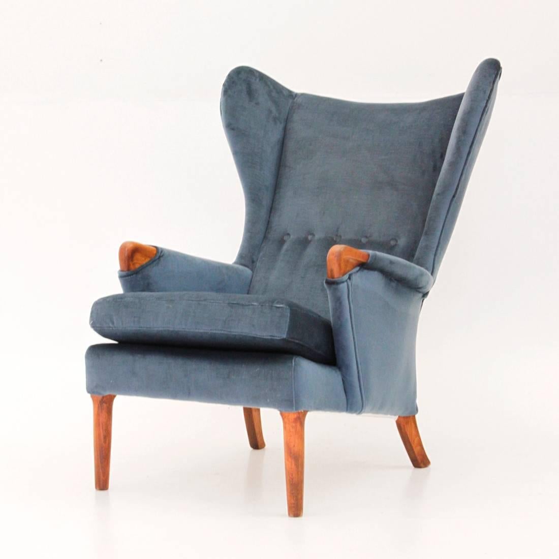 This wingback chair was made in the 1960s by British manufacturer Parker Knoll. It features an oak structure, velvet upholstery and buttons on the wingback.