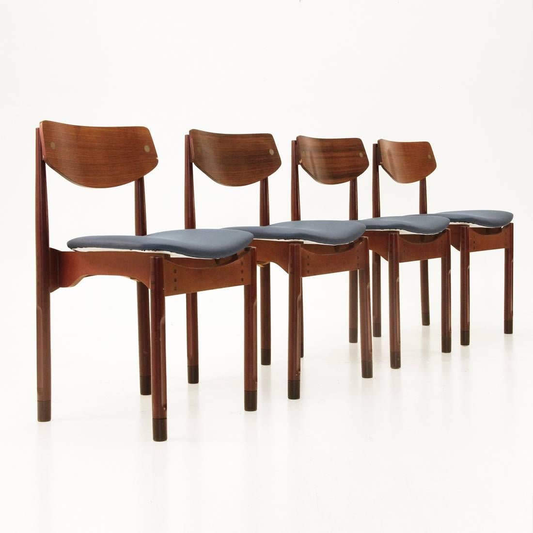 Set of four Danish-style chairs.
Italian production, 1950s.
Danish designer.
Rosewood frame.
Seat in blue faux leather.
Curved back is fixed with brass studs.
Cylindrical legs with carvings. 
Dark wood terminals.