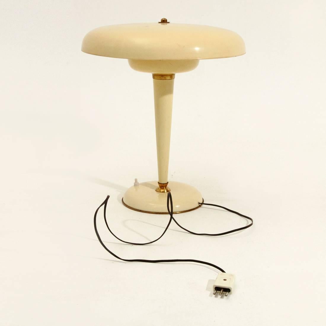 This table lamp from the 1940s is made from cream-lacquered sheet metal with brass details.