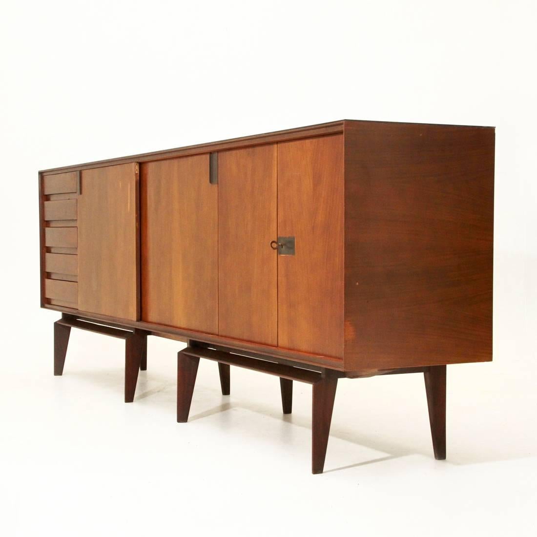 Sideboard produced by Dassi in the 1950s
Designed by Edmondo Palutari
Wooden rosewood veneered structure
Solid legs with brass details
Removable black glass top
Consisting of a chest of drawers and three compartments
Two with sliding doors and