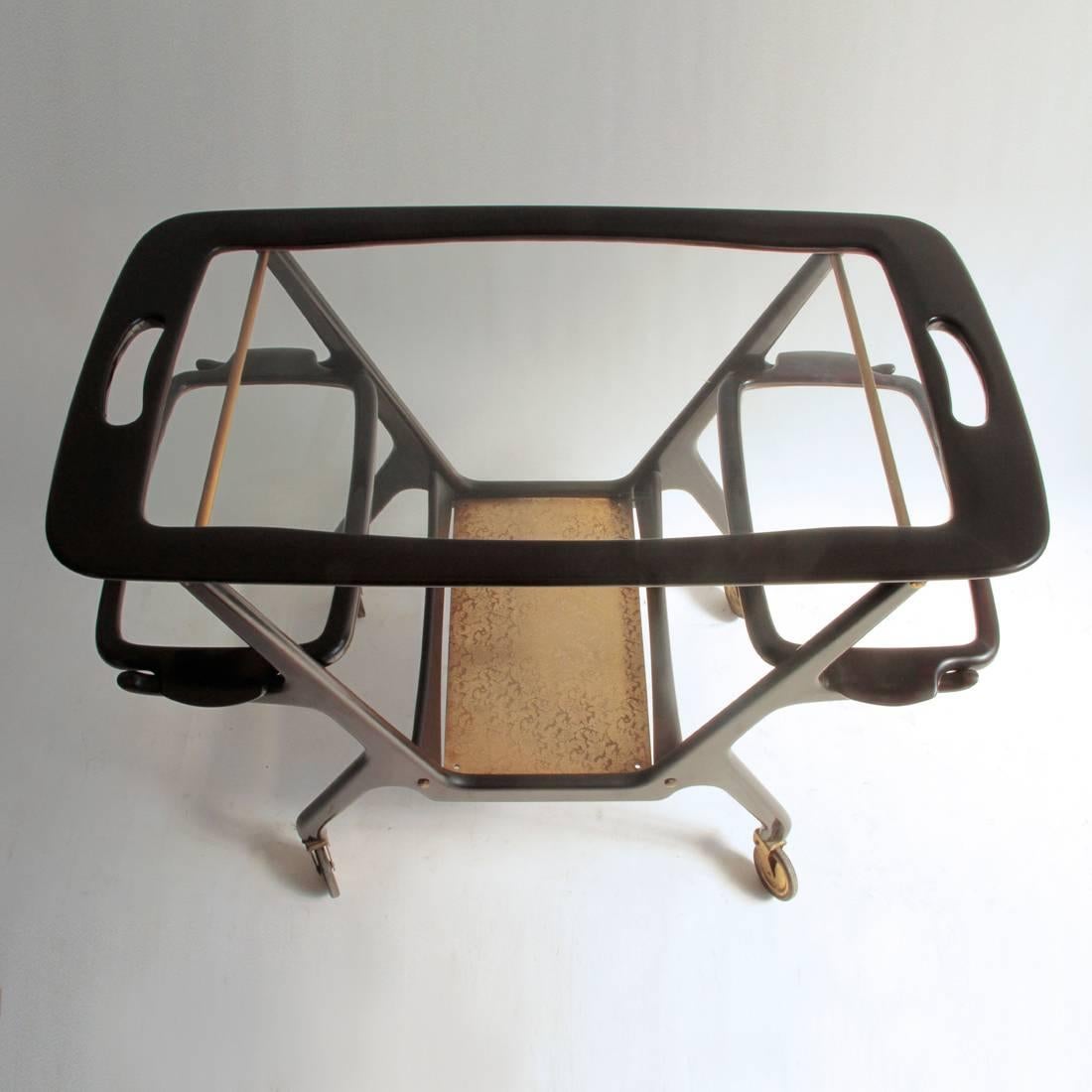 Gorgeous Trolley designed by Cesare Lacca in the 1950s.
Dark lacquered wood structure, underneath plain metal.
Side and upper top tray in glass with wood frame.
Wheels and small parts in brass.
Good general conditions, some signs due to normal