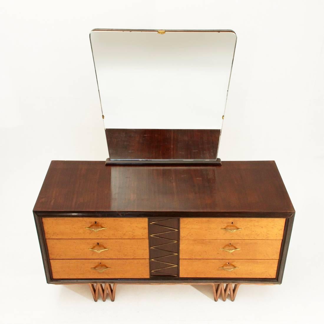 Italian furniture manufacturing in the 1940s.
Honeycomb core structure, veneered in various woods.
Framed front and central brass decoration.
Drawers with lock and brass handle in the shape of a seagull.
Shaped wood front legs painted in
