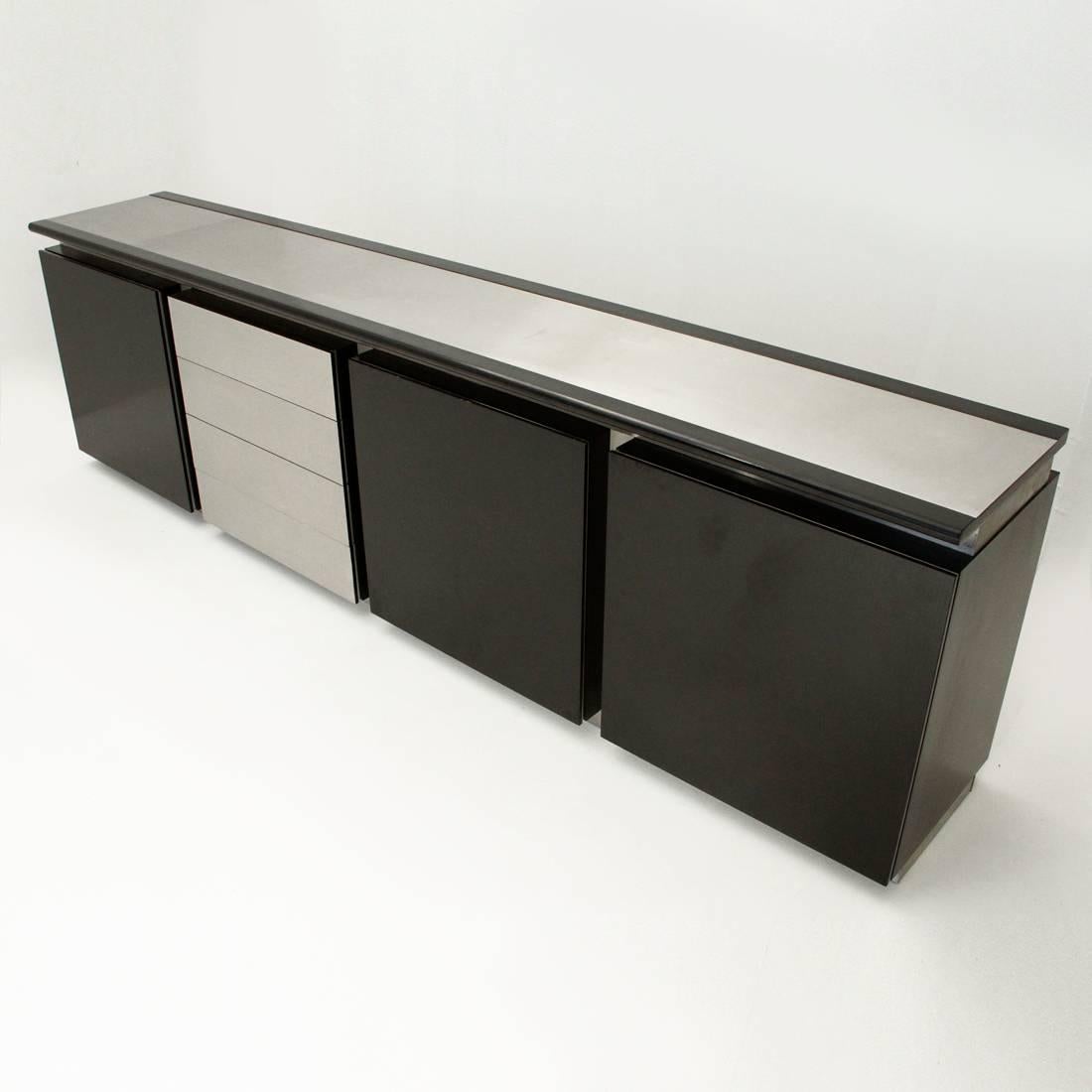 Sideboard designed in 1977 by Lodovico Acerbis and Giotto Stoppino and produced by Acerbis.
Black painted wood structure with brushed metal panels.
Formed by three elements, with leaf opening and glass shelf.
Four-drawer element
Dimensions:
