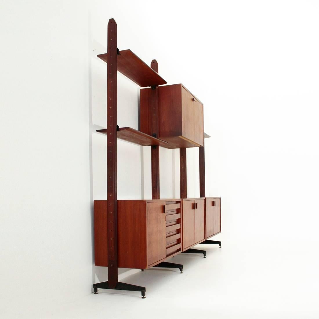 Italian Library, 1960s.
Wooden uprights with black painted metal feet and brass adjustable terminal.
Three shelves, a chest of drawers, a sloping compartment and two open-door compartments.
Good general conditions, some signs and veneers on the