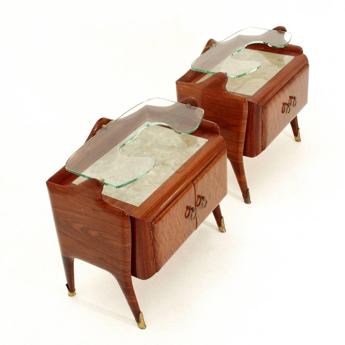 Pair of Italian nightstands produced in the 1950s.
Veneered wood structure, legs with brass tips.
Door compartment with brass handle.
Marble top and top shelf in shaped glass, with brass blocks.
Good condition, some signs due to normal use over