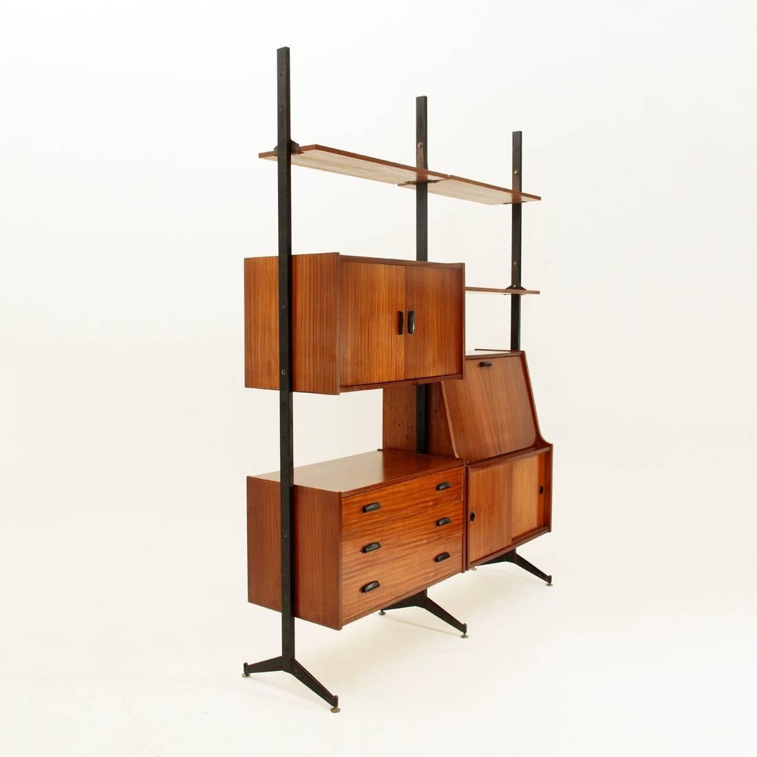 Italian wall unit of the 1960s.
Black varnished metal uprights with adjustable brass feet.
Three shelves and three container modules, black painted metal handles.
Signs of rust, some stains and veneer flaws on the wooden part.