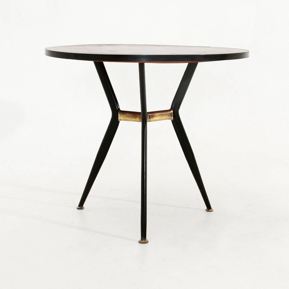 Italian coffee table from the 1960s.
Structure in black painted metal and brass.
Wood veneer top with black border.
Good general conditions, some signs on the top.

Dimensions: Diameter 60 cm, height 51 cm.