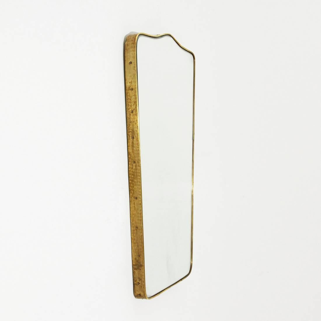 Italian mirror production of 1950s.
Wooden frame, mirrored glass with bevelled edge. Hammered brass frame.
Good general condition, some signs of wear on the mirror.

Dimensions: Width 42 cm, depth 3 cm, height 65 cm.