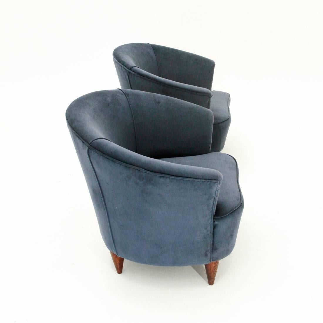A pair of Italian armchairs produced in the 1950s.
Upholstered and lined wooden structure with new blue velvet fabric.
Conical shaped turned wood feet.
Very good general conditions.

Dimensions: Width 78 cm, depth 65 cm, height 66 cm, seat