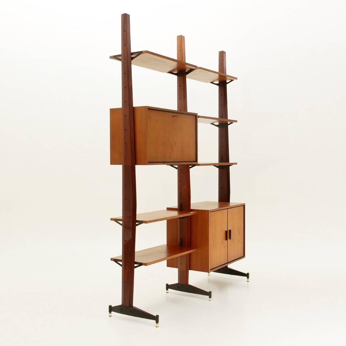 Italian teak bookcase from the 1960s.
Wooden faceted uprights,
foot in black painted metal and adjustable brass terminal.
Six shelves, one compartment with flap opening and one compartment with doors.
Good general conditions, some signs are