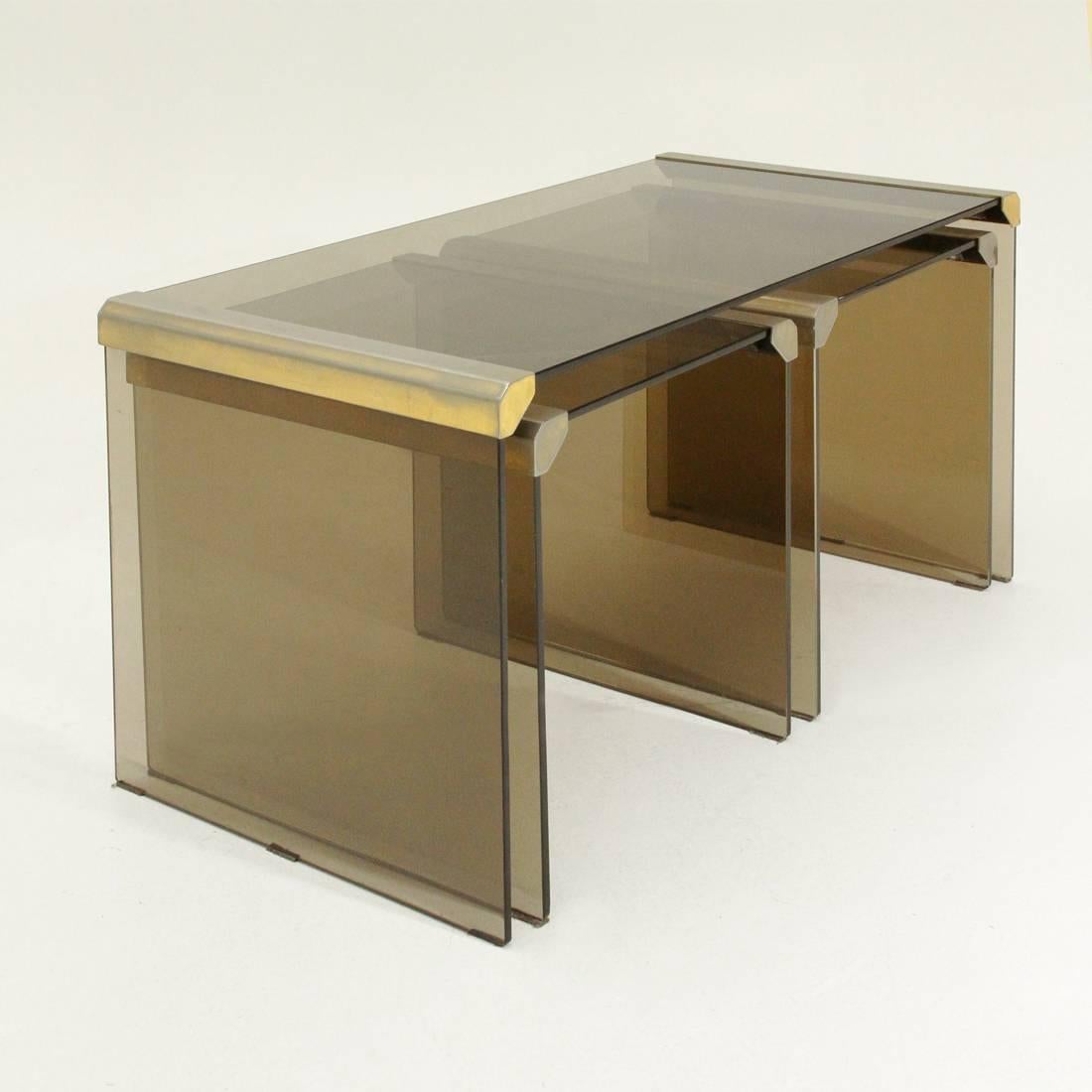 Set of three 1970s production tables designed by Pierangelo Gallotti.
Coffee tables made of smoked glass plates with brass joints.
The two small tables can be stored under the big one.
Structure in good condition, some marks on the brass