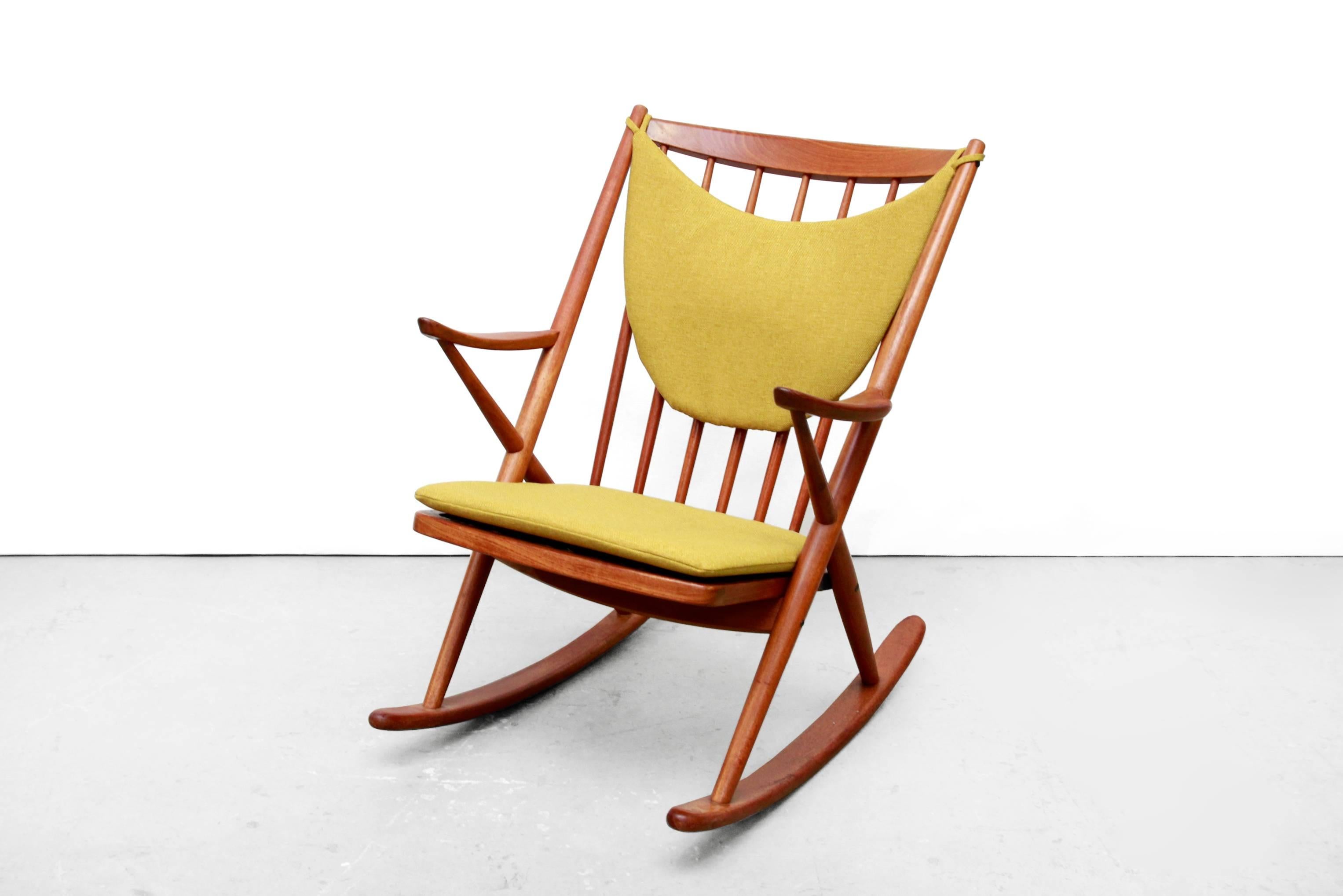 This rocking chair was designed by Frank Reenskaug in 1958 for Bramin Denmark. It is made from solid teak and features a mustard yellow seat and back cushion. The armchair with high backrest and slightly curved armrests is very comfortable. The