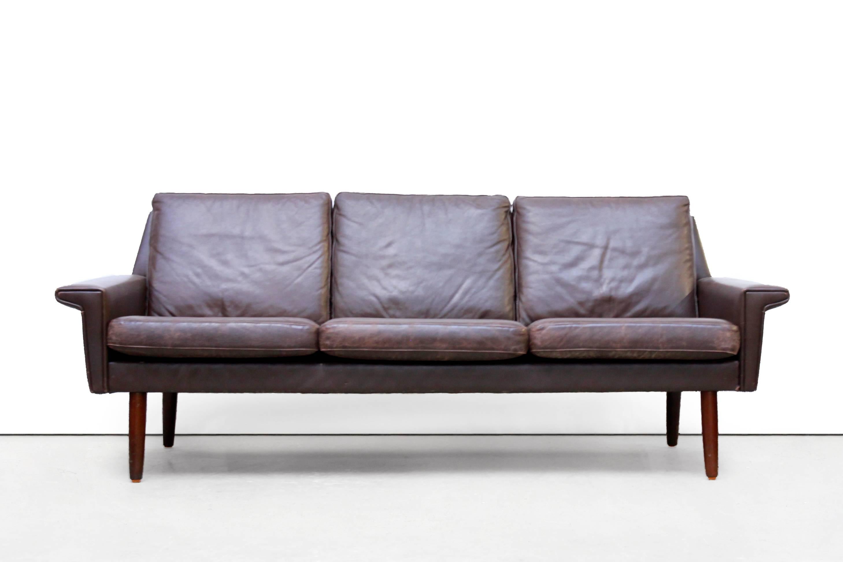 Classic Mid-Century design three-seat cushion sofa in brown patinated leather.
This three-seat sofa is made in the Vejen Polstermobelfabrik in Denmark and has teak tapered legs.