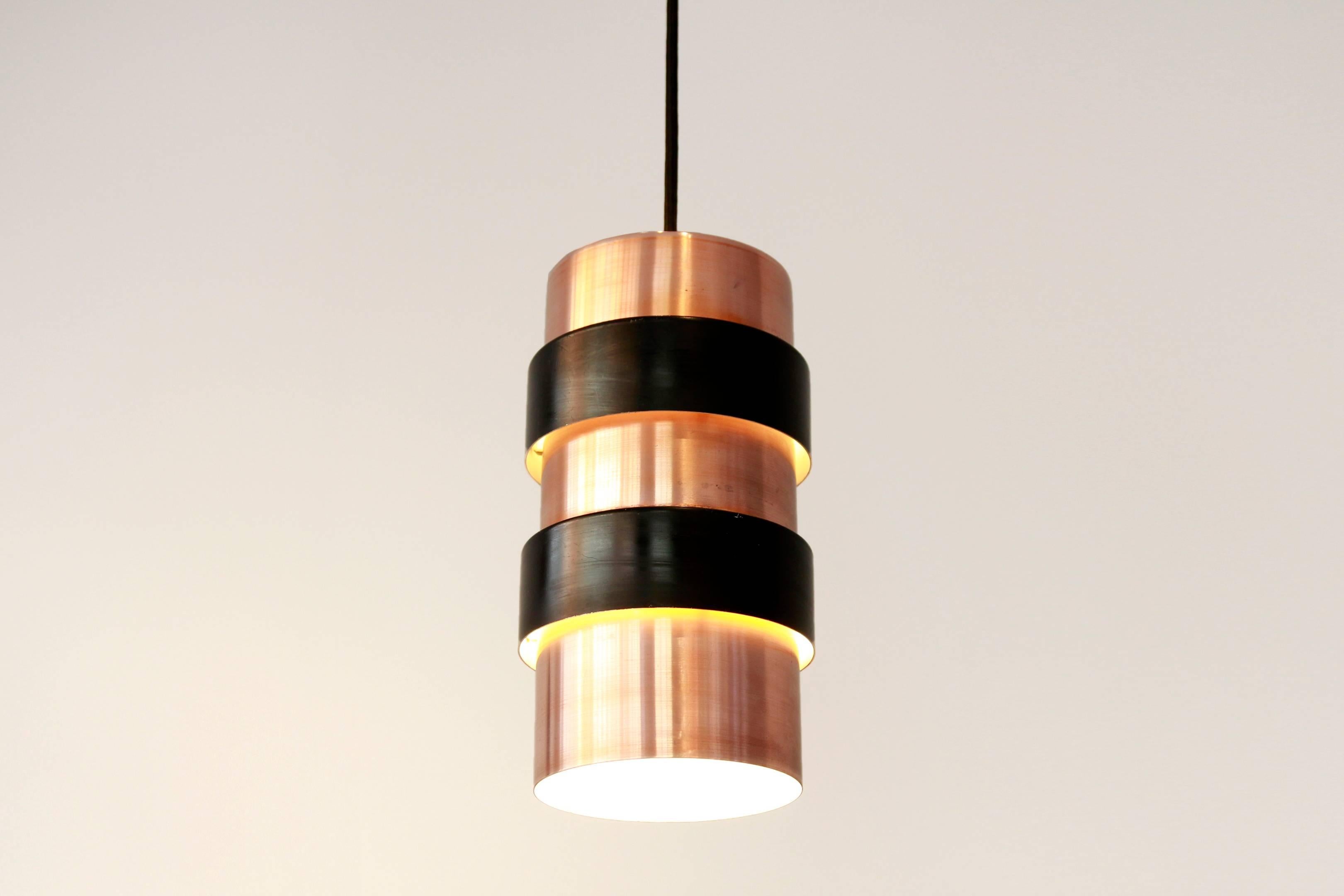 Copper pendant hanging lamp with black rings designed by Jo Hammerborg and produced by Fog and Mørup, Denmark in the sixties. The lamp has a standard E27 fitting and a new black fabric cable.