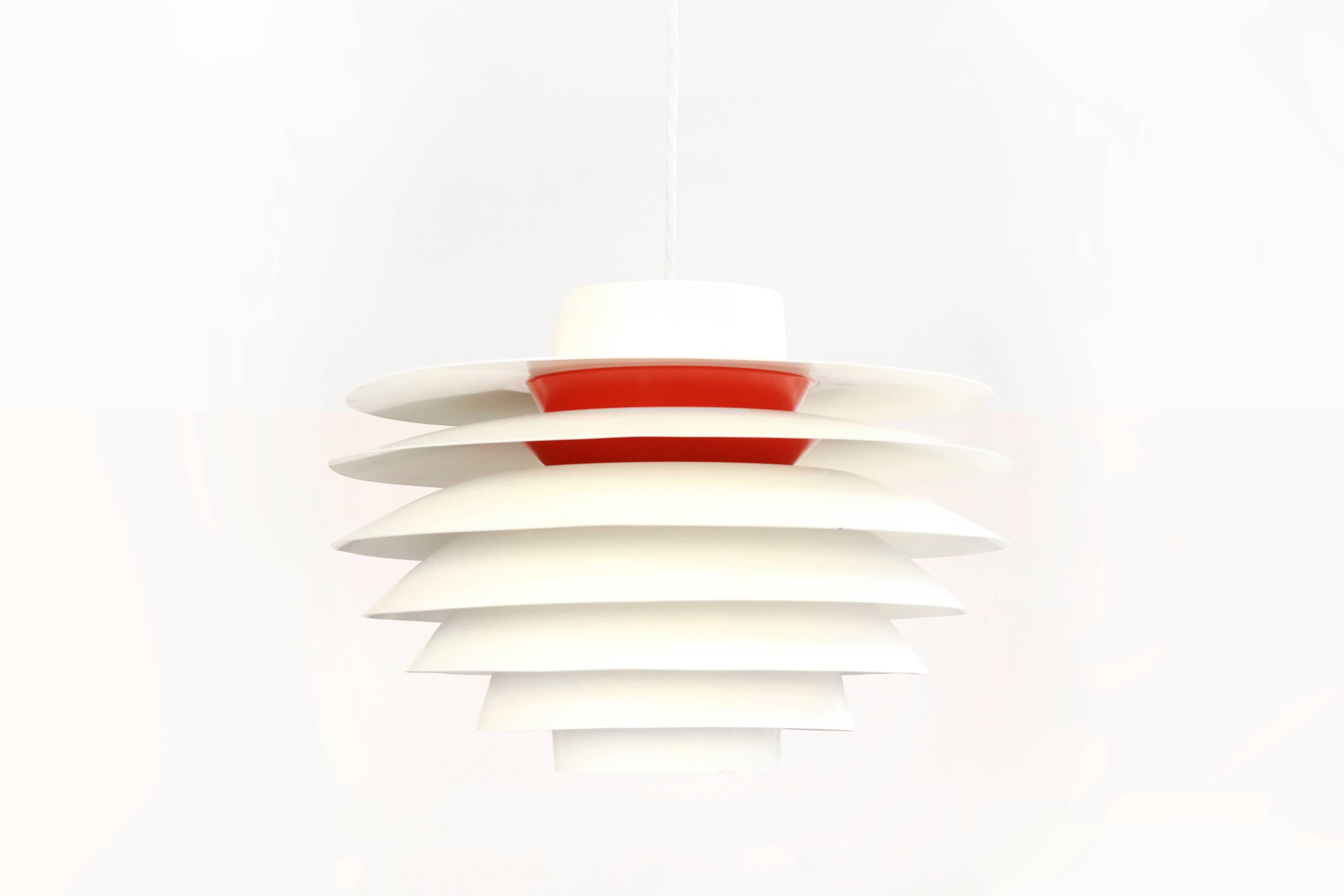 This Verona pendant lamp was designed by S. Middelboe for Nordisk Solar Compagni in Denmark in 1962.
It is made from aluminium and features a orange /red lacquered interior.
The model name of this lamp is 