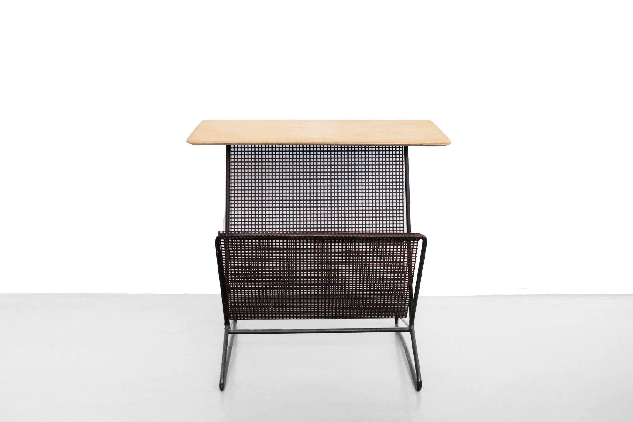 This Minimalist table with magazine rack was designed by Cees Braakman for Pastoe. It has model name TM05 from the Combex series. This rare side table is made from a black-lacquered frame, with a perforated magazine rack and a birch plywood