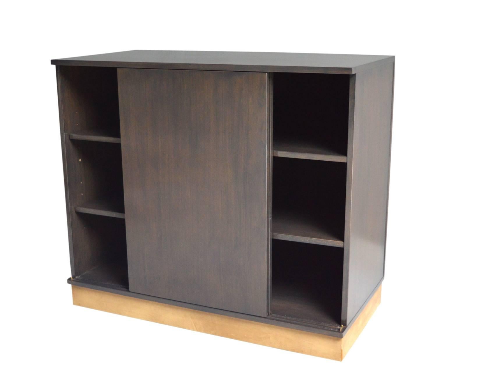 Handsome walnut cabinet by Edward Wormley for Dunbar. Three inner shelves with sliding doors. Bottom of cabinet is wrapped in tan leather. Dunbar tag on the back. Newly refinished in grey. Perfect size. Matching cabinet without doors also available