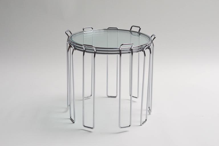 Classic set of chrome and glass nesting tables by Saporiti. Circular tables look great stacked together or apart. Tables sit on rectangular hairpin legs with tabs at the top. Tables are in excellent vintage condition. Perfect cocktail tables for