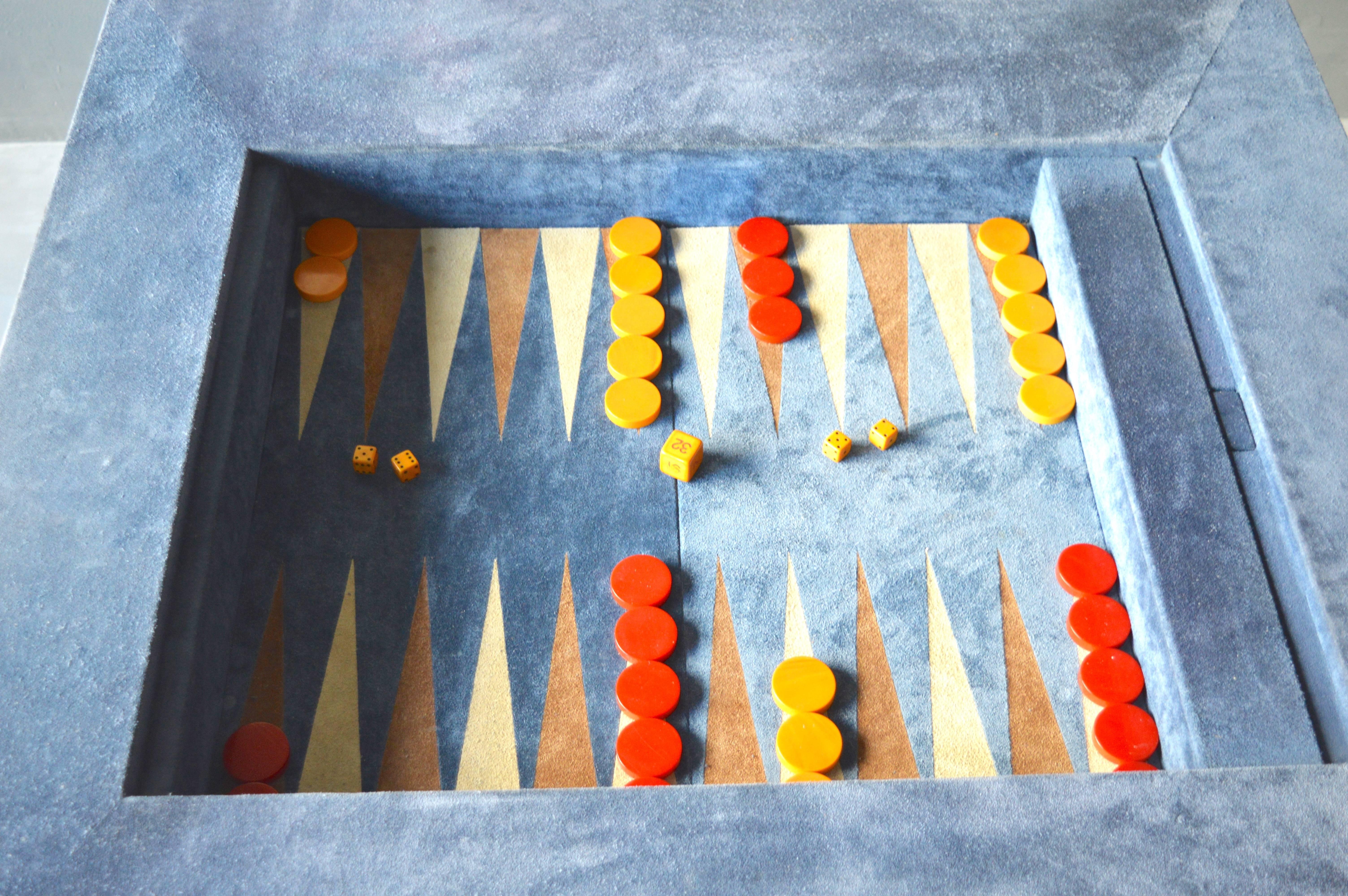 Great vintage backgammon table in a blueish or gray suede. Table comes with a complete set of red and mustard yellow bakelite backgammon pips, two sets of bone dice and bone doubling cube. Inset compartment for storing game pieces. Removable
