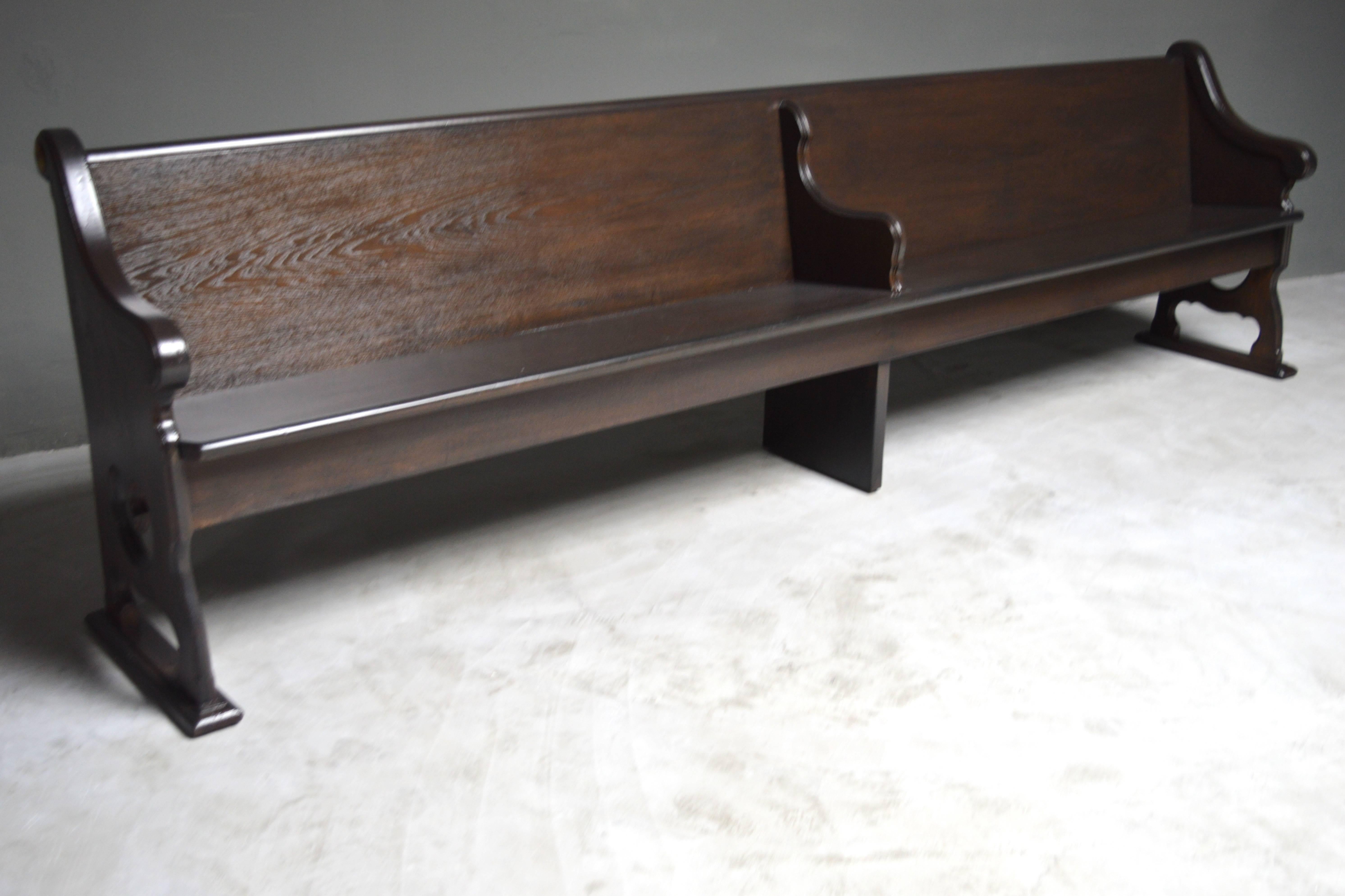 Massive 10 foot long church bench. Newly refinished in a light ebony. Extremely sturdy and substantial piece. Bench features center divider and arm rests on both ends. There is a brass disc on each side of the bench labeled 