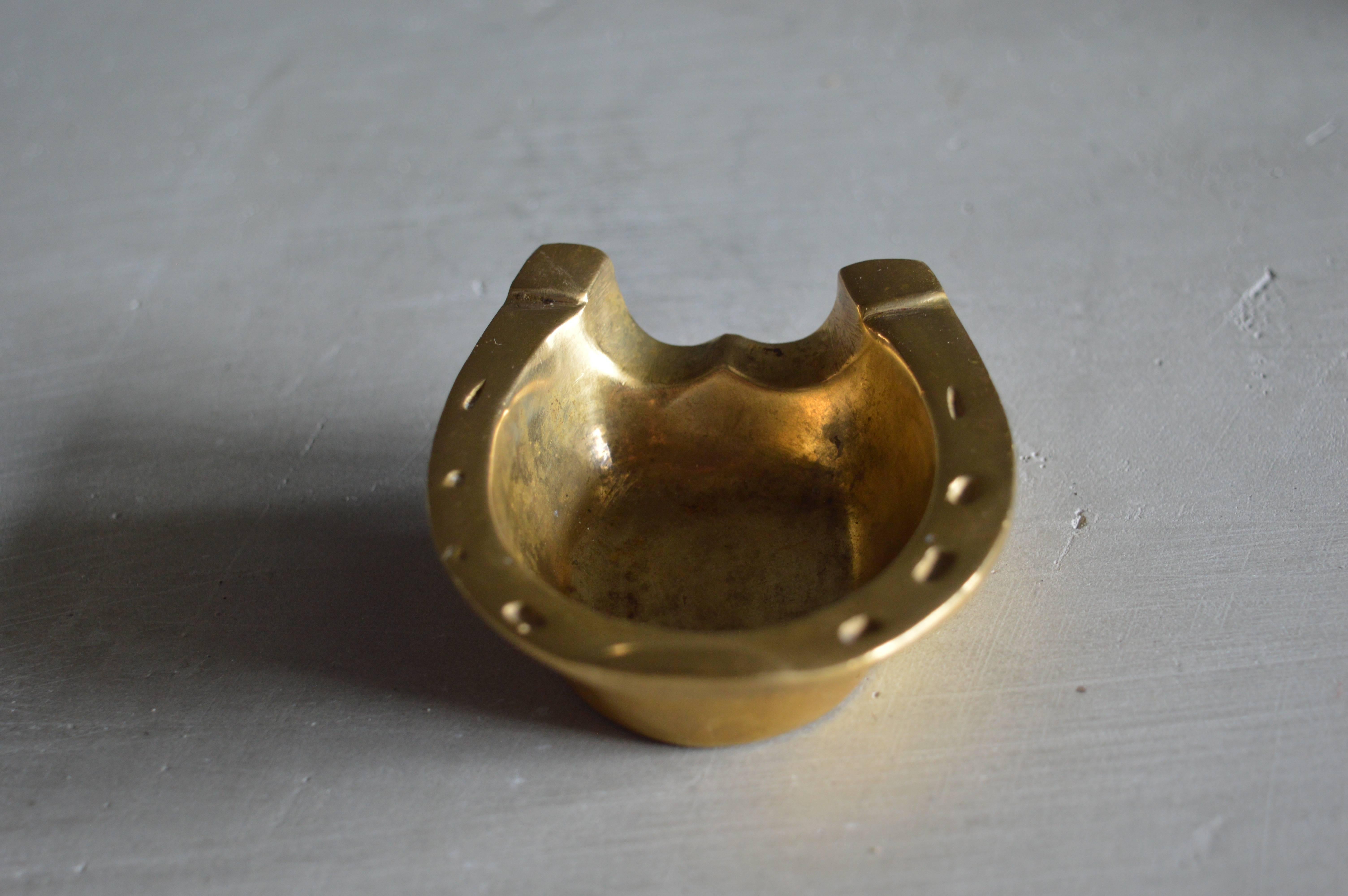 Petite French brass ashtray in the shape of a horseshoe. Very solid and heavy piece. Excellent patina to brass.