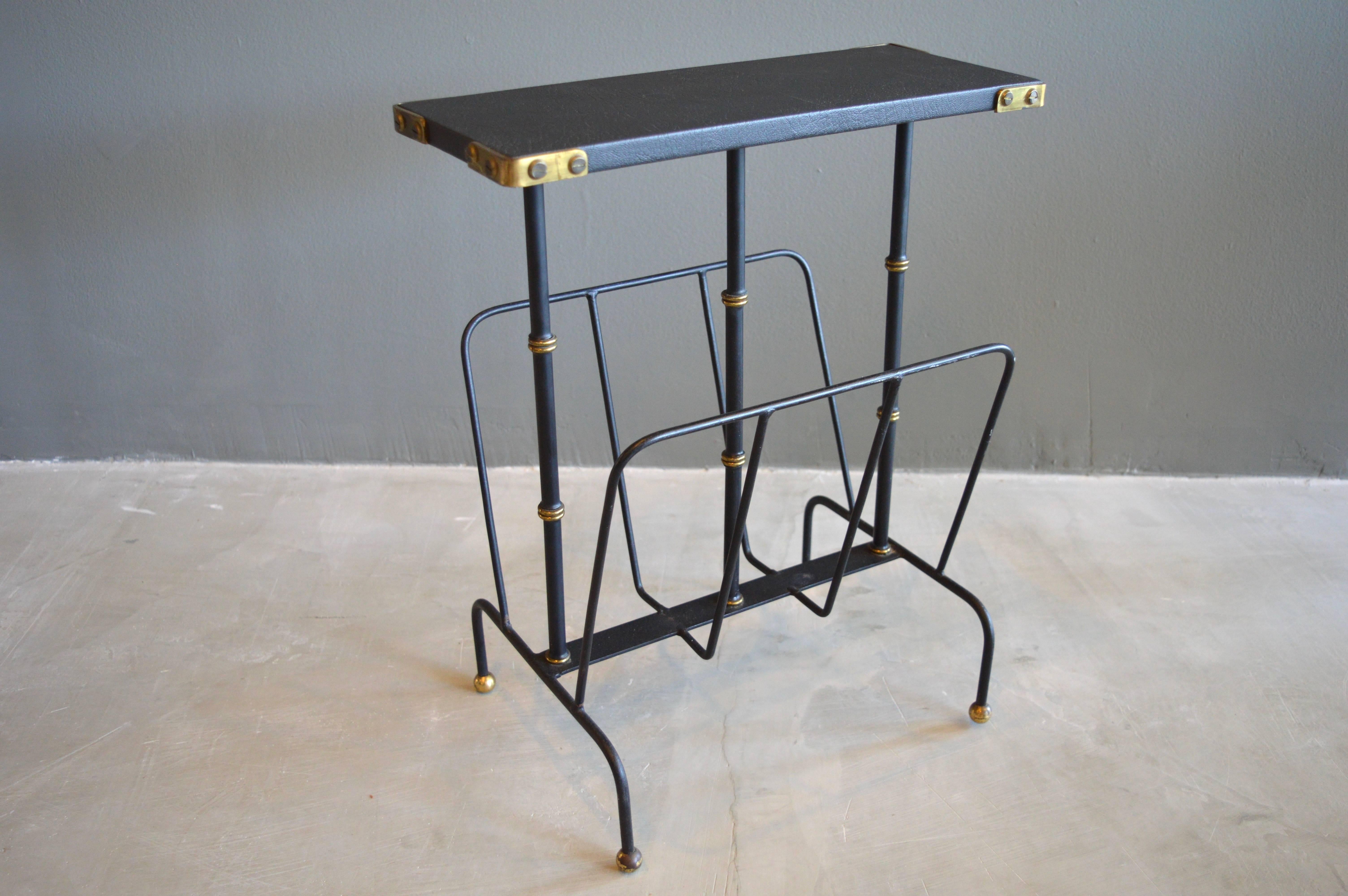 Handsome side table/magazine rack by French designer Jacques Adnet. Original black leather with brass detailing. Excellent vintage condition.