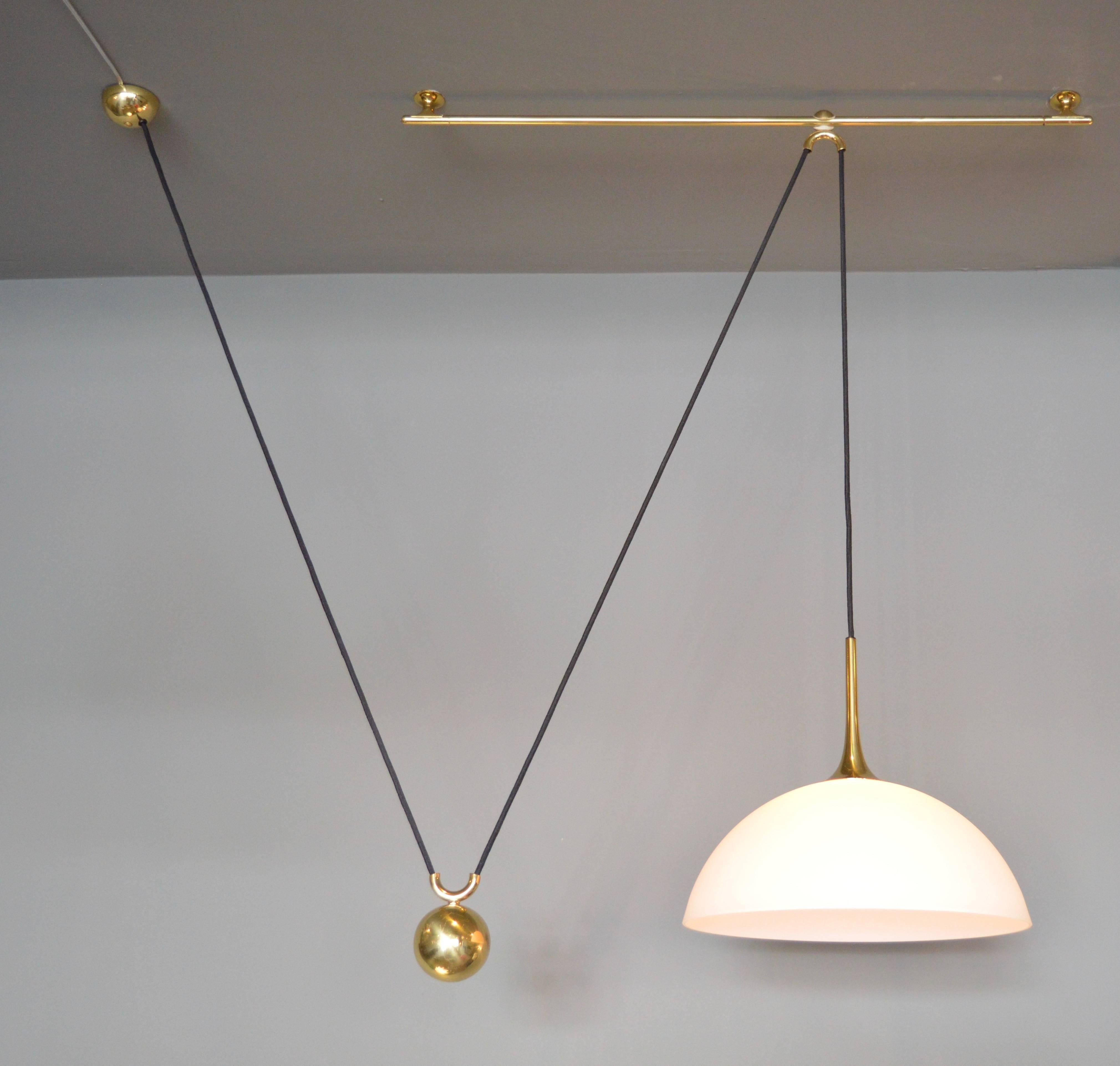 Unique counter balance pendant by Florian Schulz. Pendant features an opaque glass shade with brass stem, canopy, counter weight and brass rod. Pendant can be pulled up or down easily on the cloth cord and can also slide forward and backward on the