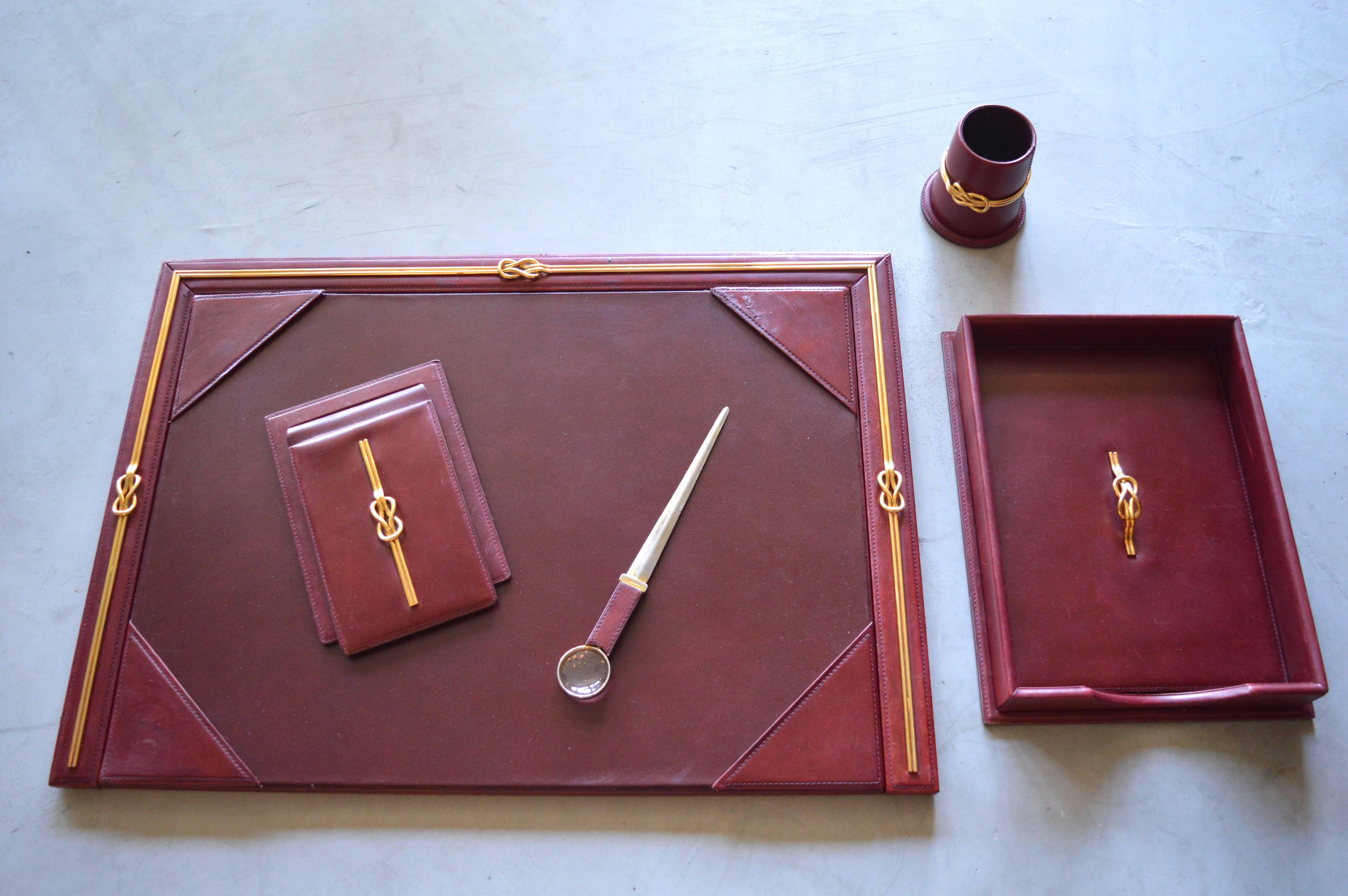 Gorgeous Gucci desk set in leather and brass. Deep red leather has excellent patina. Set includes: Large desk blotter, notepad holder, pen cup, large letter tray with cover and letter opener with magnifying glass tip. All pieces marked Gucci.