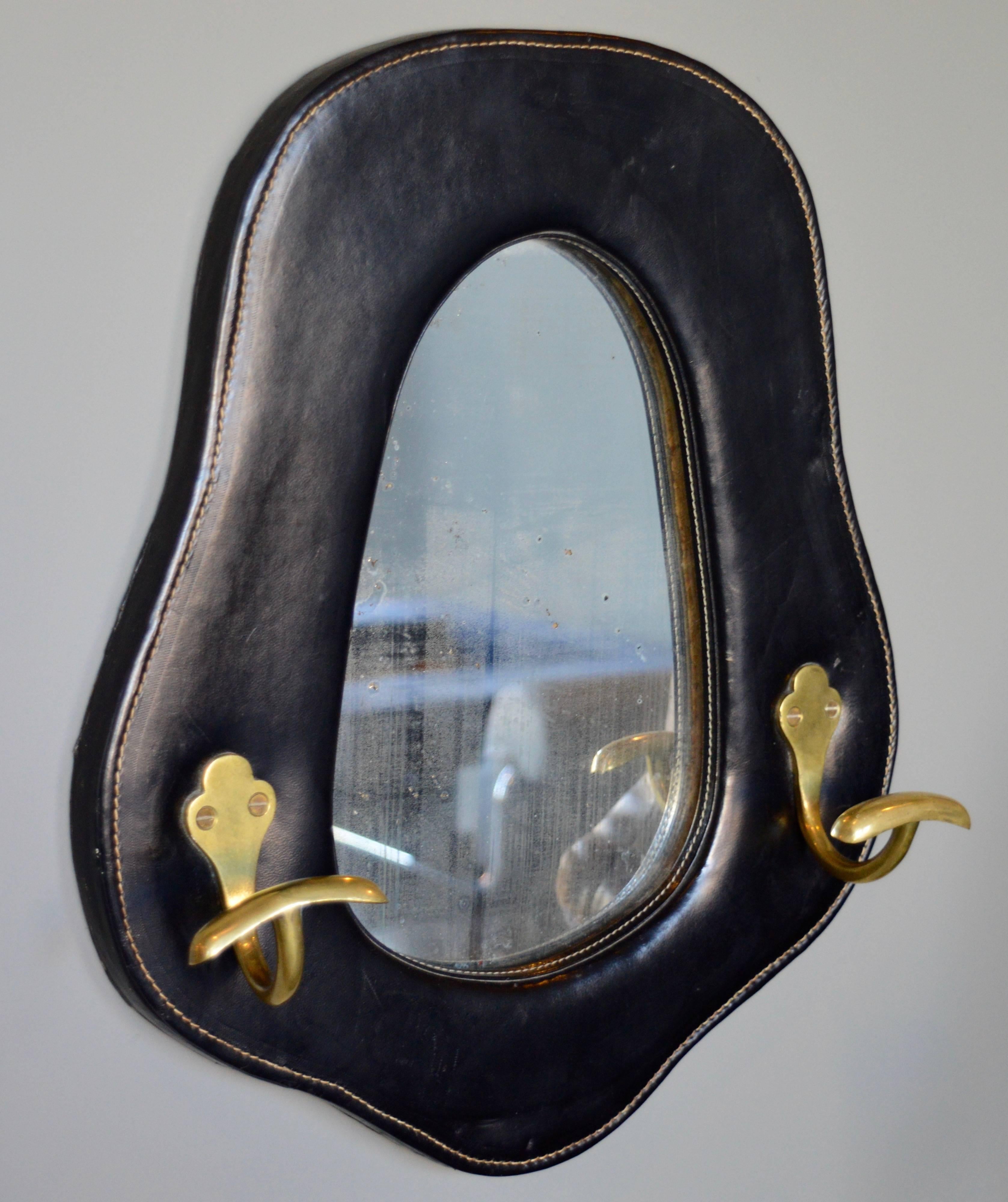 Handsome leather and brass mirror by French designer Jacques Adnet. Signature Adnet contrast stitching and excellent patina to black leather. Mirror is naturally aged and looks great. Excellent vintage condition.