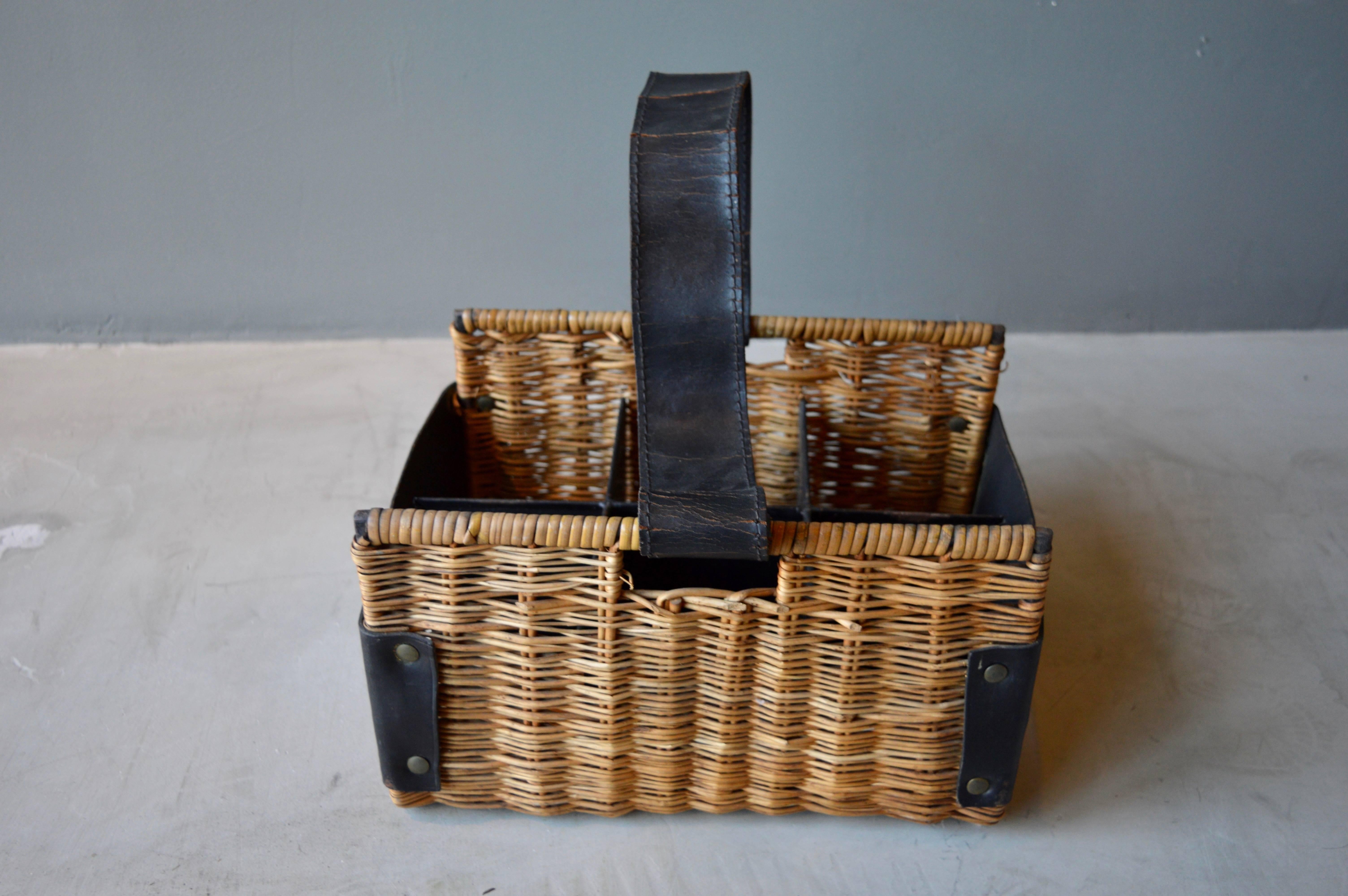 Handsome wine basket by French designer Jacques Adnet. Rattan in excellent vintage condition. Leather in good vintage condition. Very unique piece.