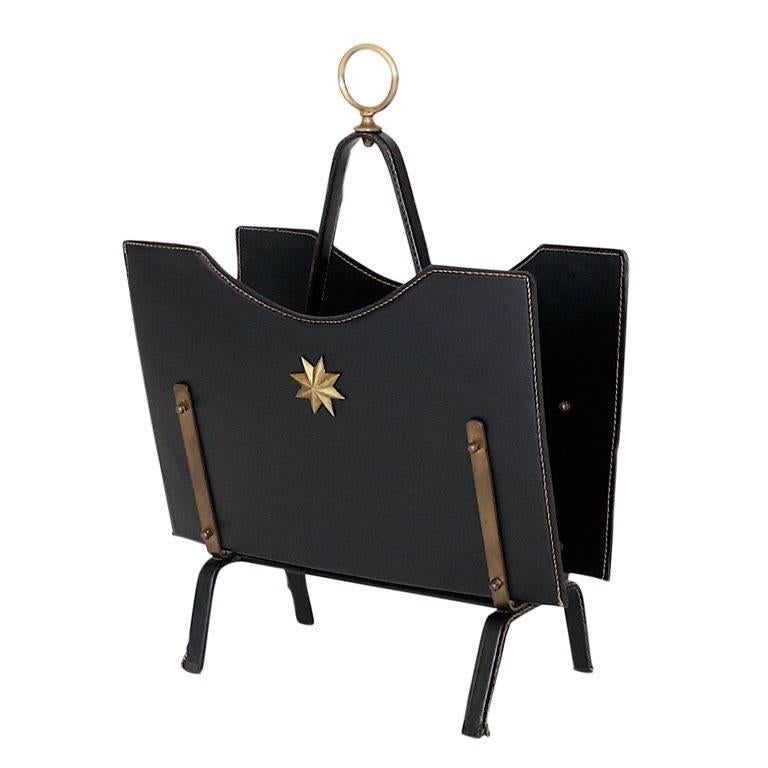 Stunning leather and brass magazine rack by French designer Jacques Adnet. Great patina to brass. Leather in excellent condition. Signature Adnet contrast stitching throughout.