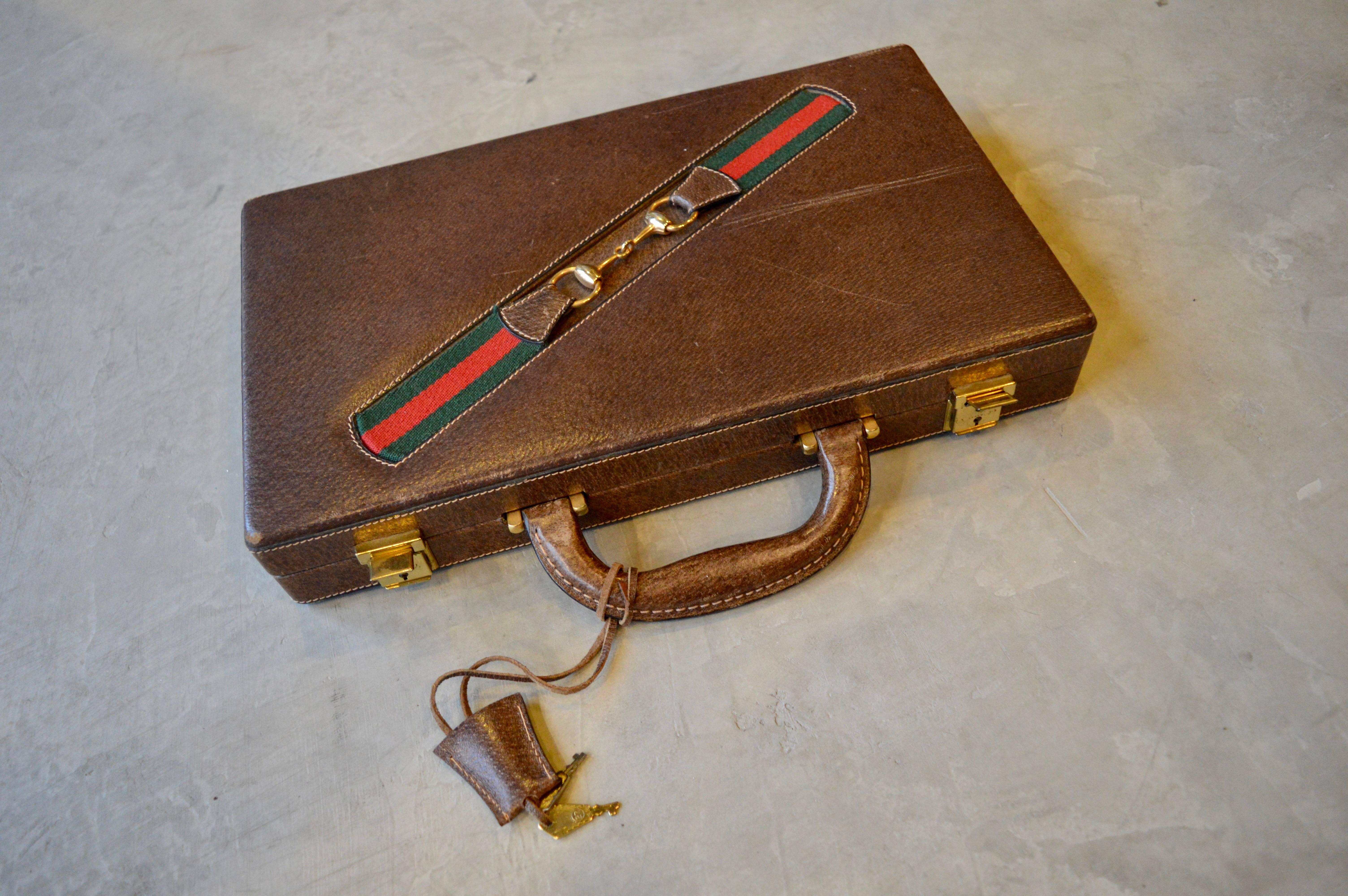 Handsome vintage Gucci backgammon set. Leather case with all pieces inside. Two leather cups, 15 black checkers, 15 white checkers and a set of red and green dice. Original key included. Brass closures on case not in working order. Otherwise set is